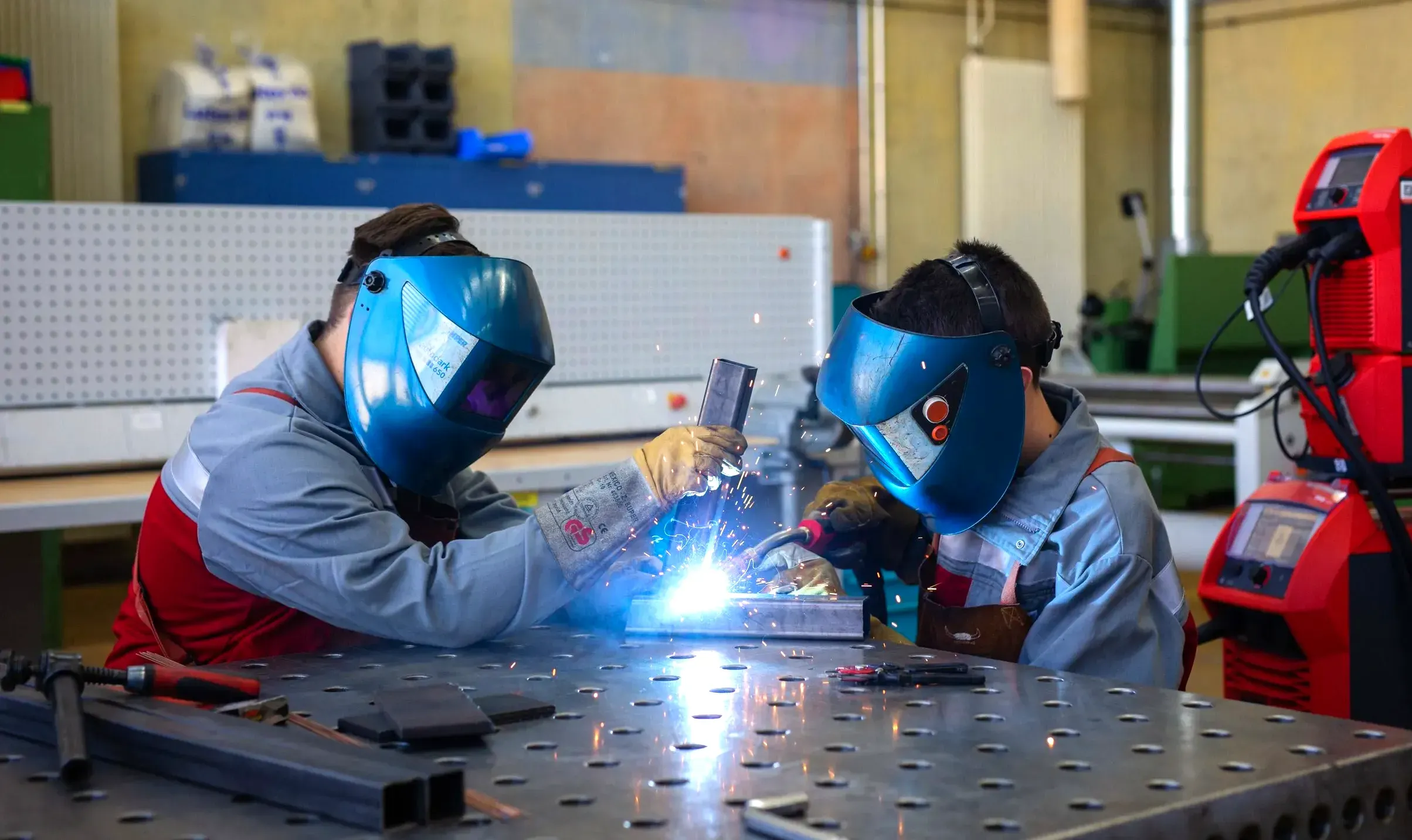 Zwei Personen in Schutzhelmen schweißen Metall in einer Werkstatt bei N-ERGIE Aktiengesellschaft.