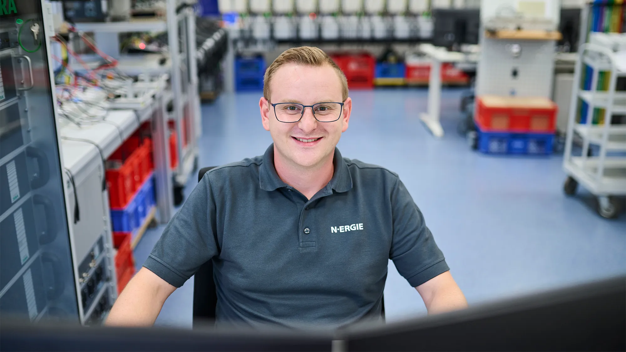 Ein Mitarbeiter von N-ERGIE arbeitet lächelnd an einem Computer im modernen Techniklabor des Energieunternehmens.