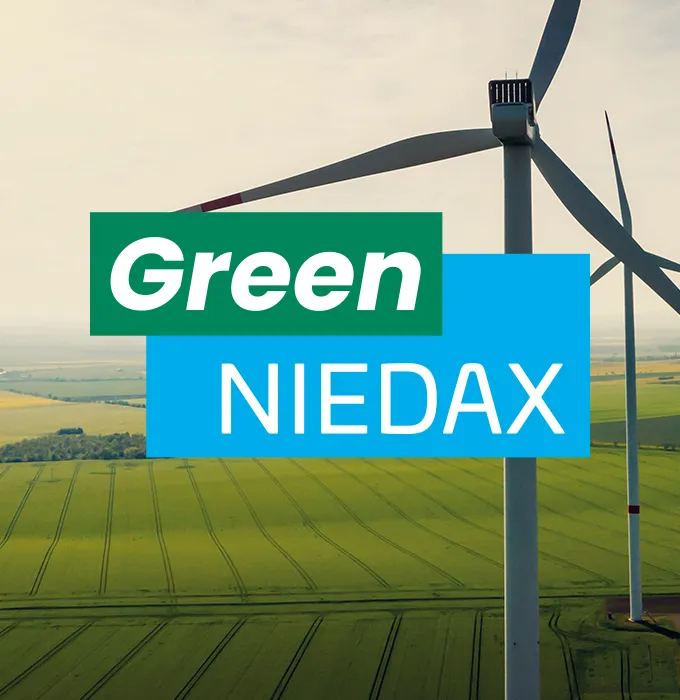 Windkraftanlage auf grünem Feld mit "Green Niedax"-Text im Vordergrund, symbolisiert nachhaltige Produktion.