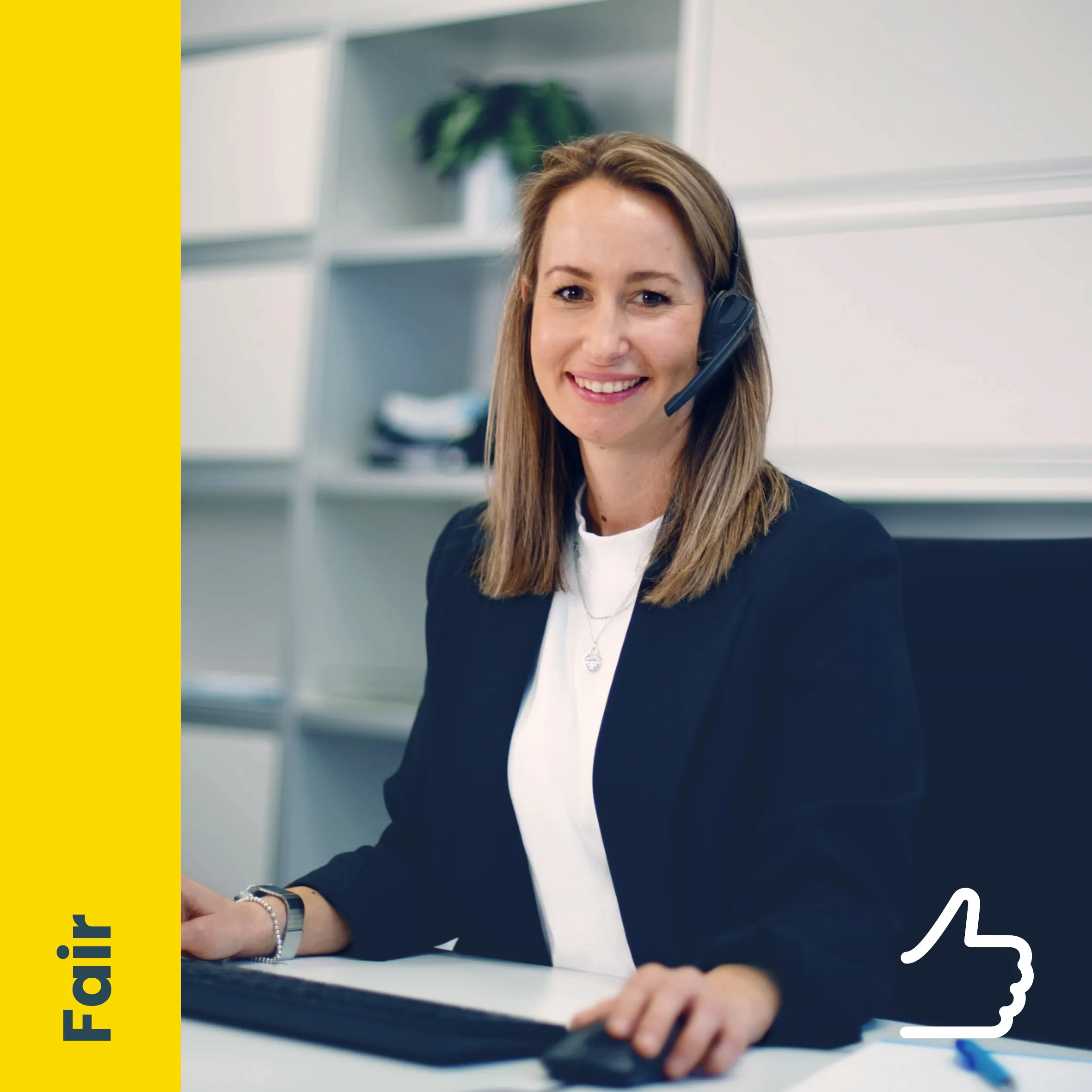 Eine Frau mit Headset lächelt am Schreibtisch im Büro bei Niedax und tippt auf der Tastatur.