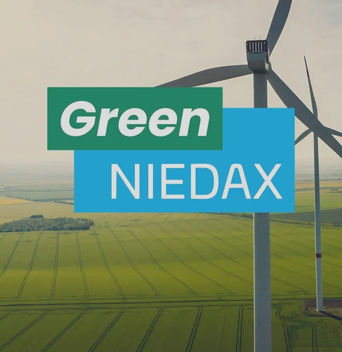 Windkraftanlage auf grünem Feld mit "Green Niedax"-Text im Vordergrund, symbolisiert nachhaltige Produktion.