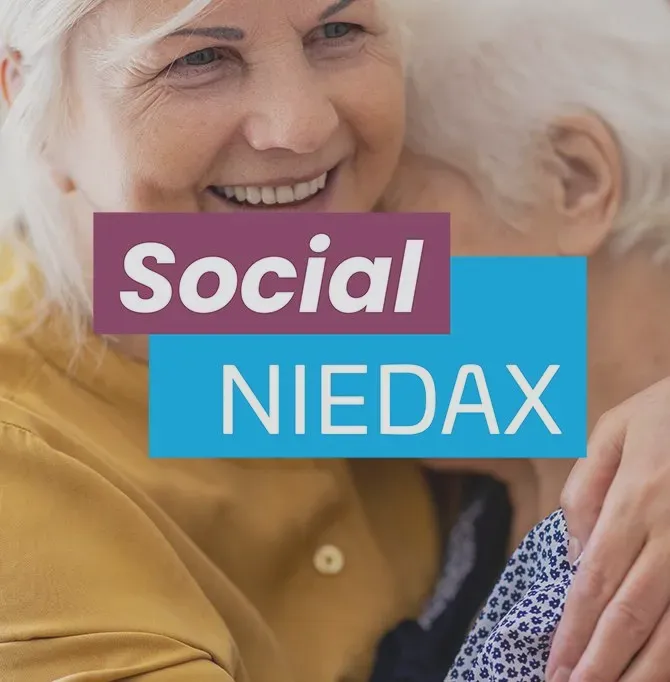 Zwei ältere Personen umarmen sich lächelnd, mit dem Text 'Social Niedax' darüber.