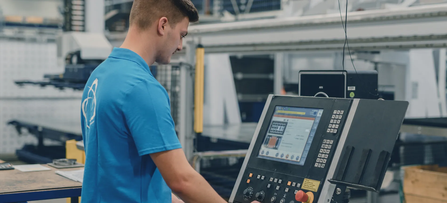 Ein Techniker bedient ein CNC-Bedienfeld in einer industriellen Umgebung.