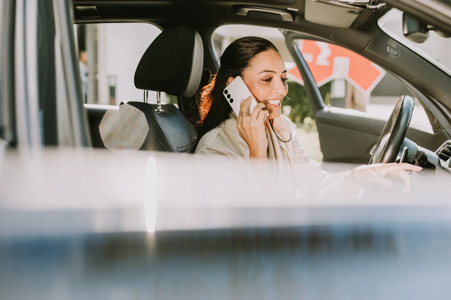 Eine Frau telefoniert lächelnd im Auto. Perfekt für flexible Arbeitszeiten und mobile Kommunikation im Pharma-Bereich.