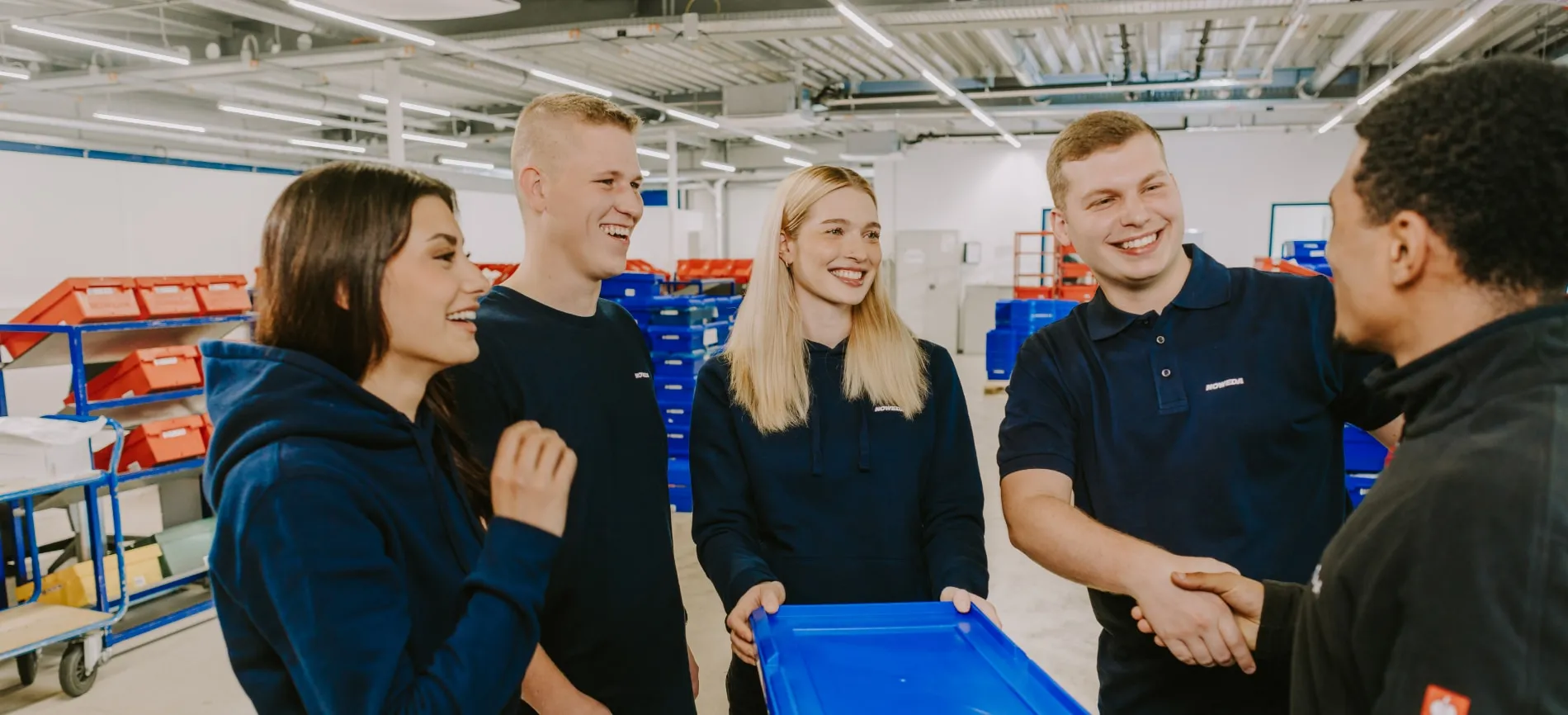 Junge Teammitglieder von NOWEDA begrüßen Dich freundlich und arbeiten gemeinsam im Lager der Pharmaindustrie.