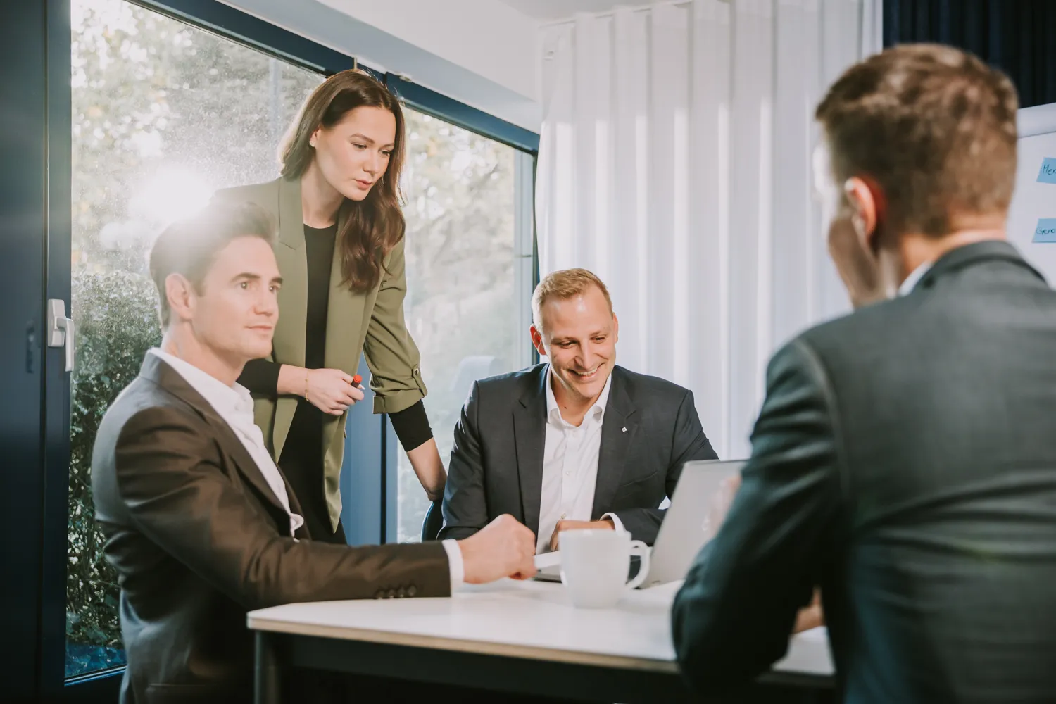 Eine Gruppe von vier Kollegen diskutiert konzentriert an einem Tisch in einem hellen Büro.