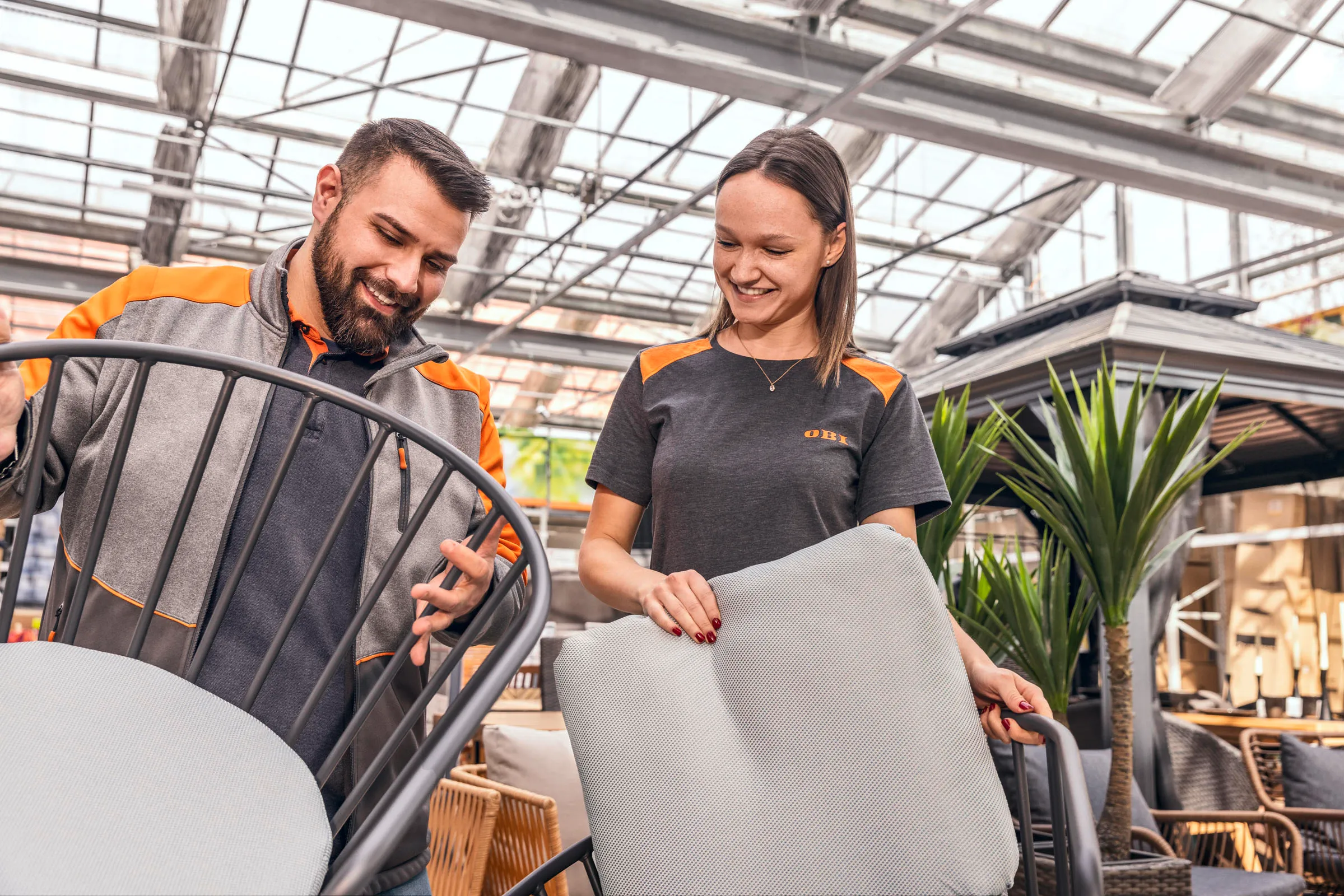 Zwei OBI Mitarbeitende beraten sich im Baumarkt über Farbmuster für die Kundenberatung.