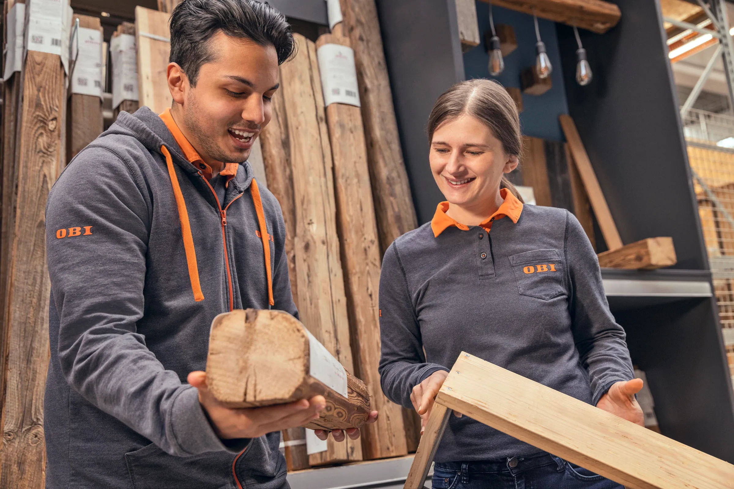 Zwei OBI-Mitarbeitende beraten dich freundlich zu Holzprodukten in der Baumarkt-Abteilung.