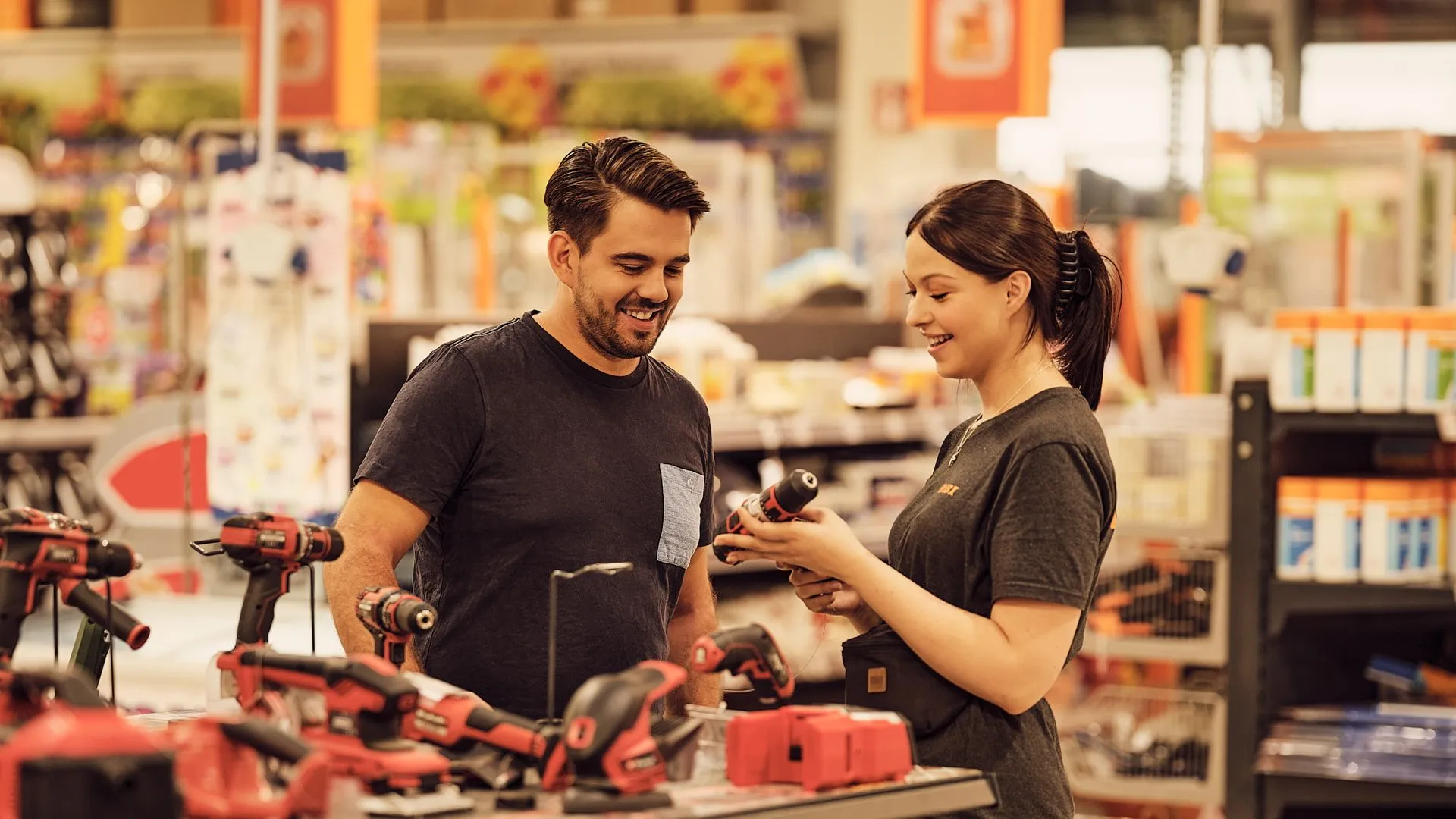 OBI Mitarbeiterin berät Dich freundlich zu Elektrowerkzeugen in einem gut sortierten Baumarkt.