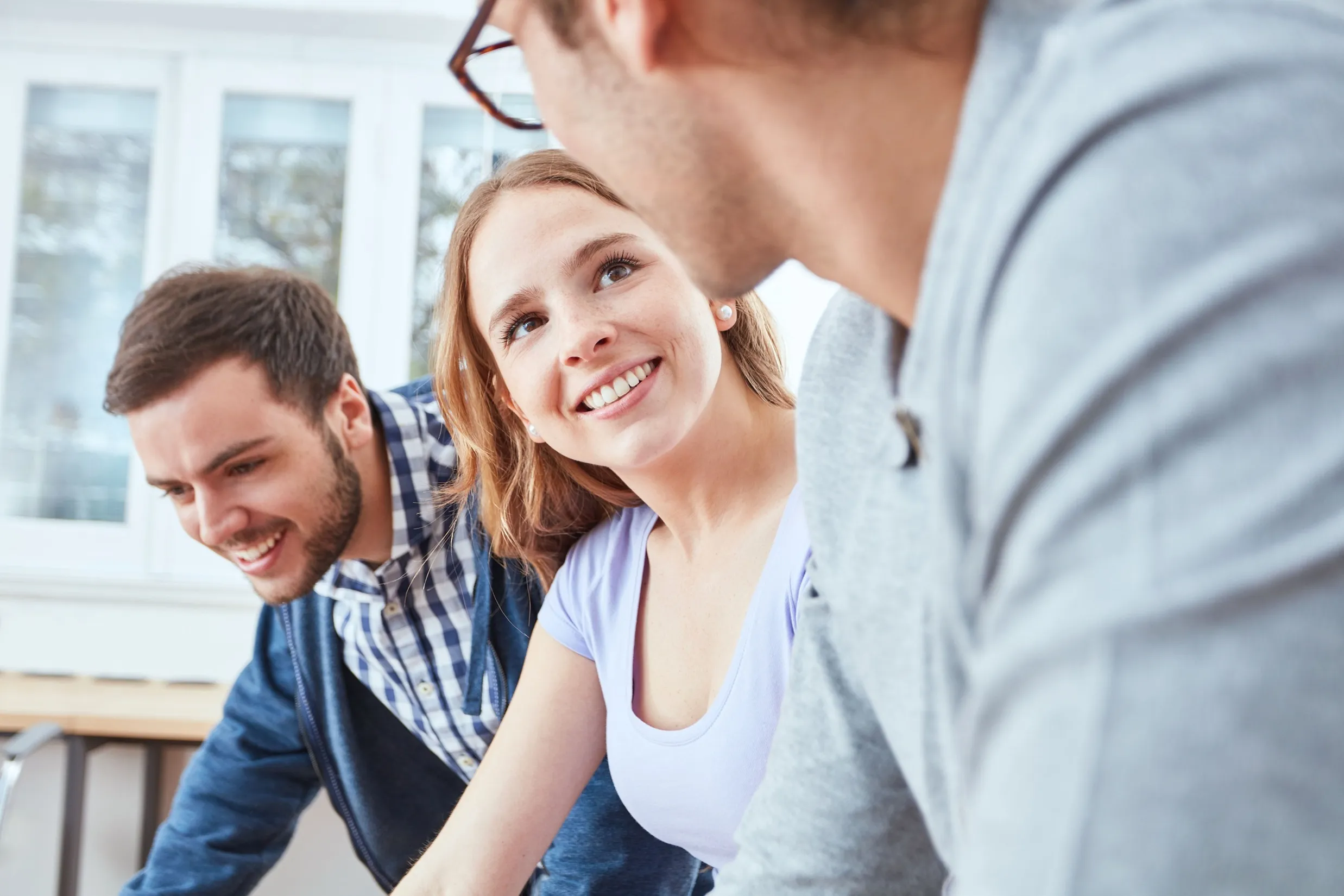 Drei Kolleg*innen in einem freundlichen Gespräch in einem modernen Büro. Perfekt für den Teamgeist bei opta data Gruppe.