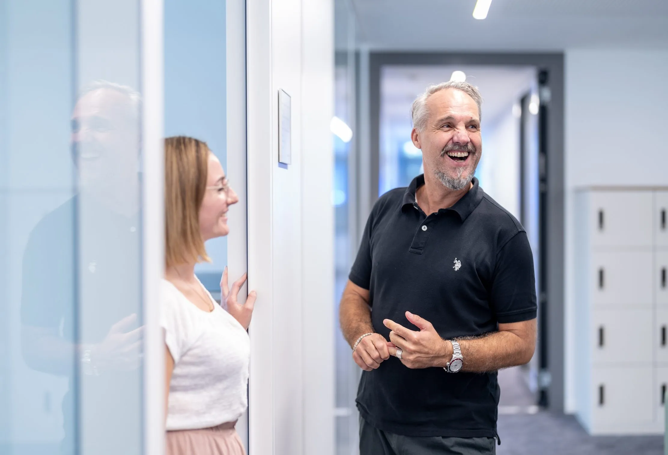 Zwei Kollegen stehen lachend im Flur des opta data Campus.