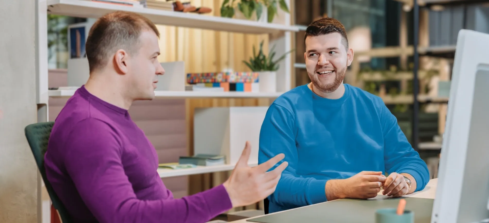 Zwei Kollegen im IT-Bereich unterhalten sich freundlich im modernen Büro von ORDAT.