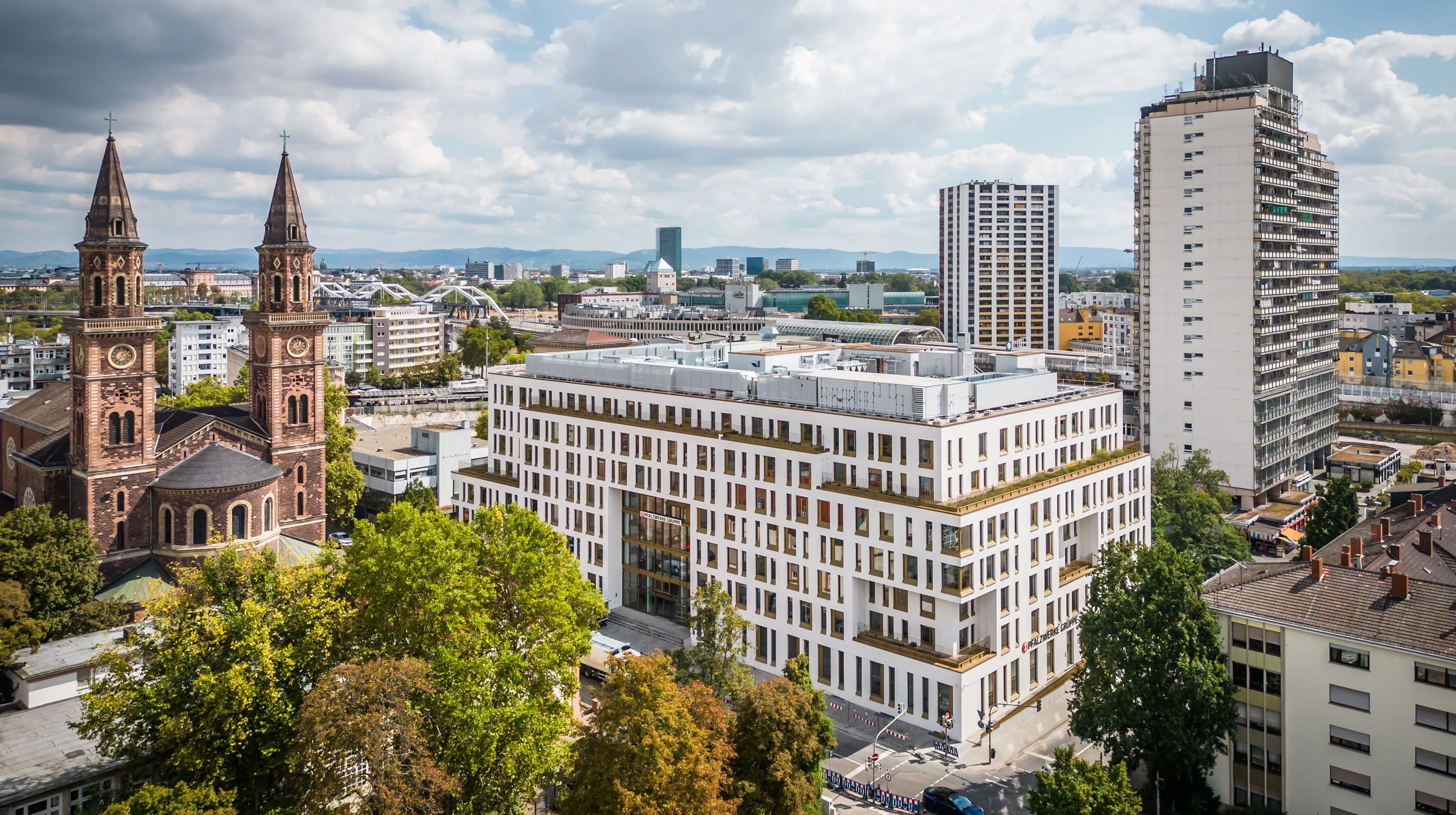 Stadtansicht mit modernen Bürogebäuden und einem historischen Kirchturm, repräsentativ für Pfalzwerke AG in der Energiebranche.