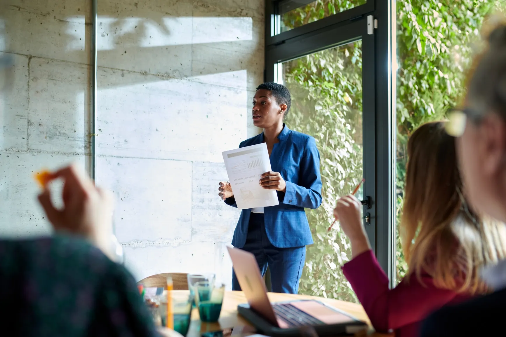 A team member in a blue suit leads a casual meeting at Ratepay, chatting finance with colleagues around a table.