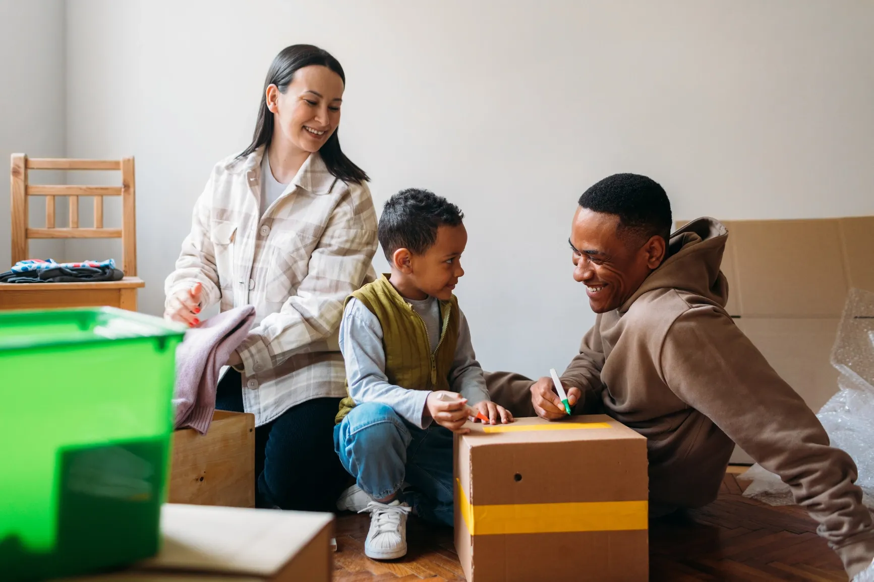 A cheerful family packing and labeling boxes together at home, showing balance between work and life.