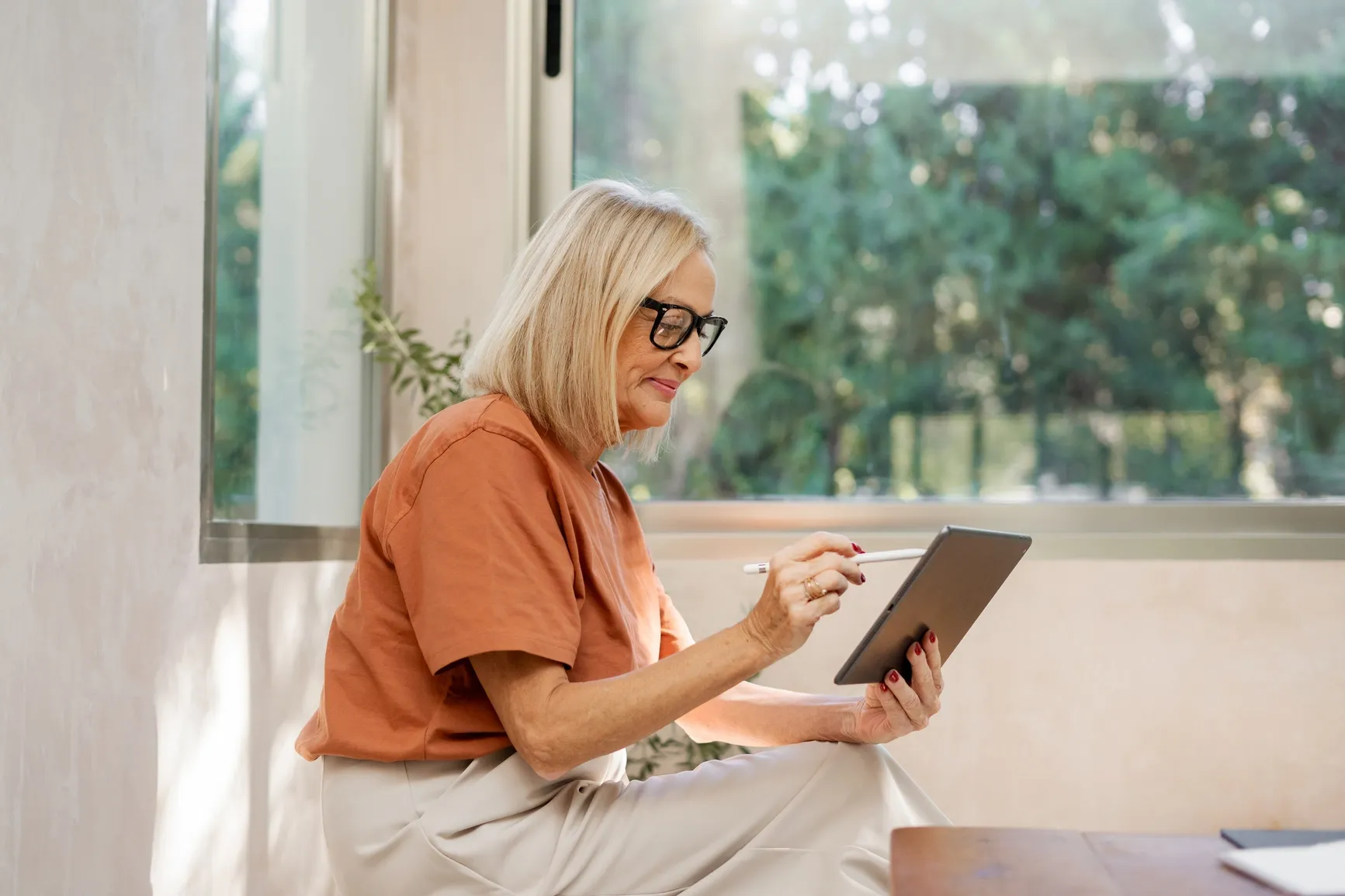 A relaxed professional working on a tablet by the window, showing flexible work at ratepay in finance and banking.