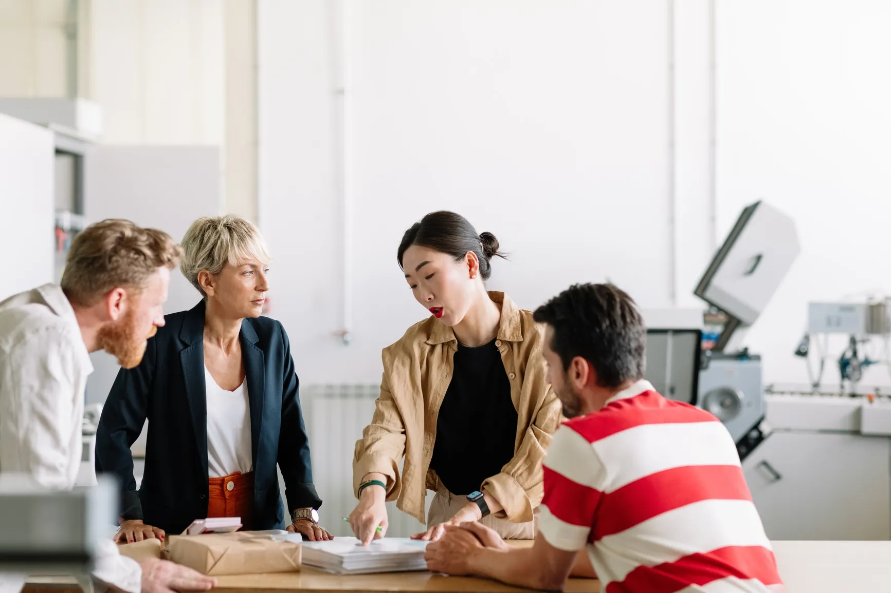 A small team at Ratepay chatting and brainstorming together around a table in a bright, modern office.