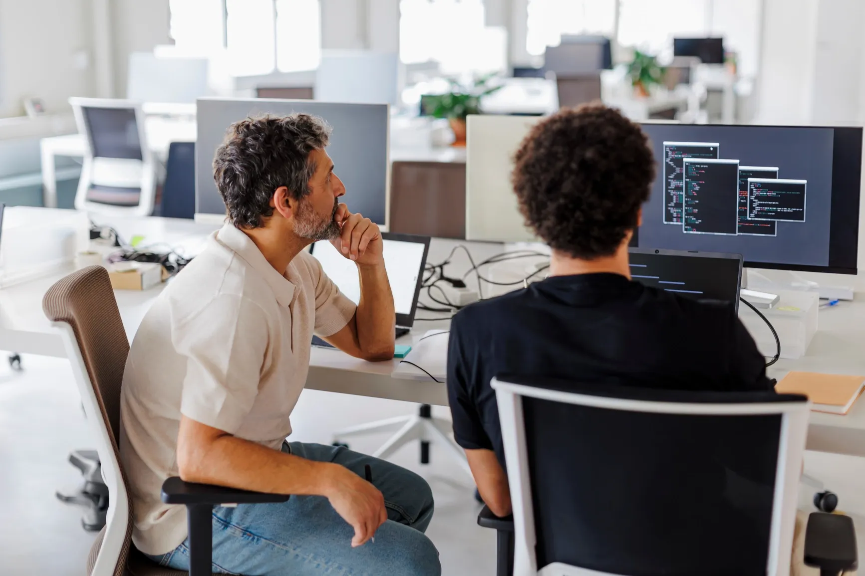 Two teammates at Ratepay brainstorming together while looking at code on a computer screen in a bright, modern office.