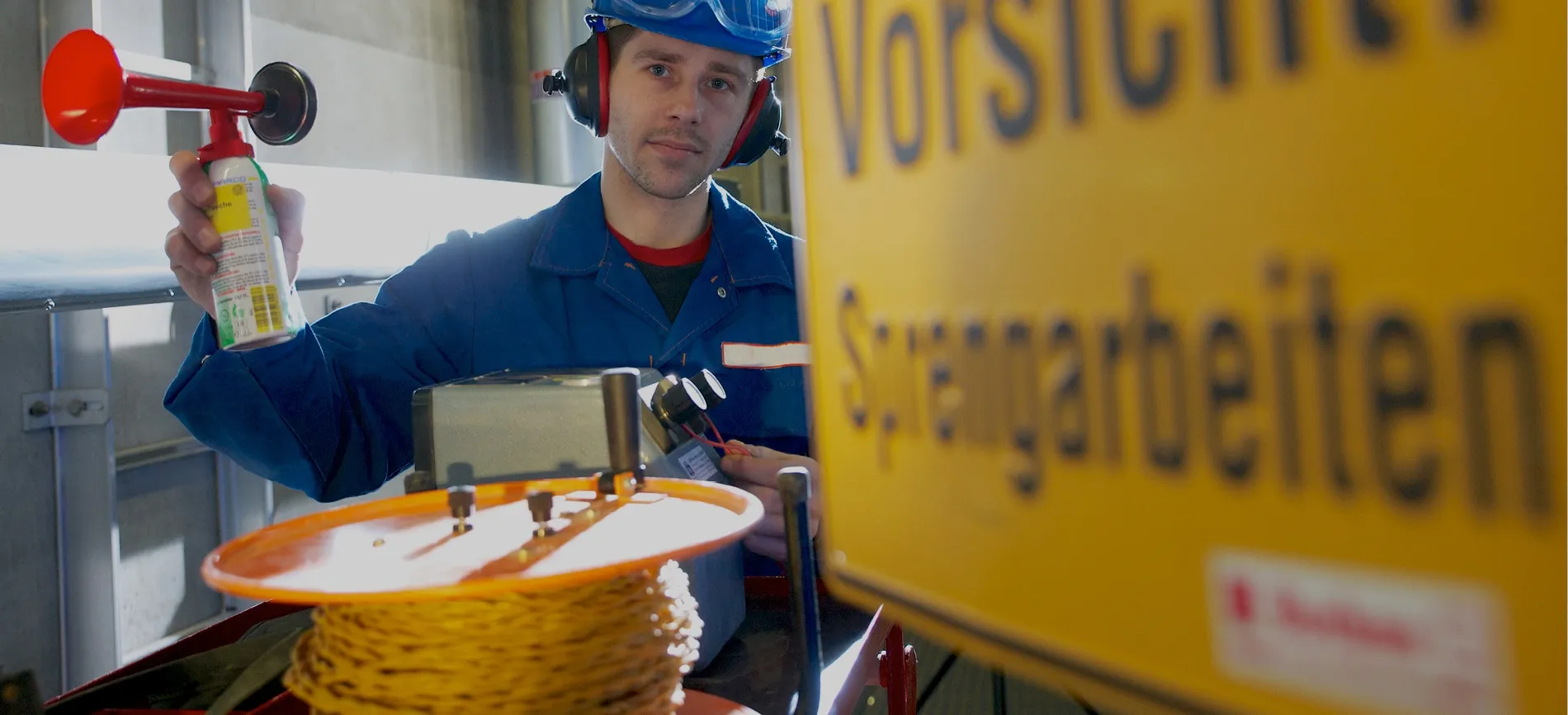 Ein Mitarbeiter mit Schutzkleidung bereitet Sprengarbeiten im Bereich Energie und Entsorgung vor.