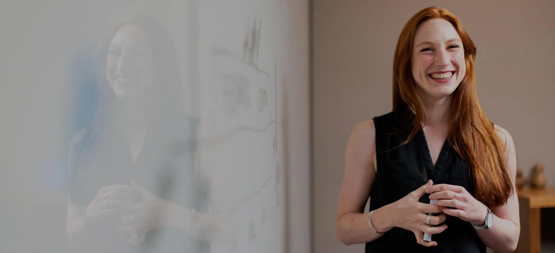 Junge Frau steht lächelnd an einem Whiteboard und lädt dich zu einer Karriere bei REMONDIS im Bereich Energie und Umwelt ein.