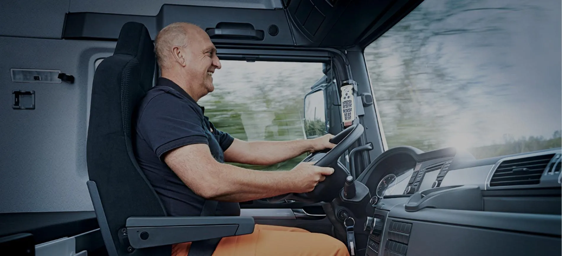 Ein lächelnder Lkw-Fahrer sitzt am Steuer und fährt für REMONDIS im Bereich Energie und Entsorgung.