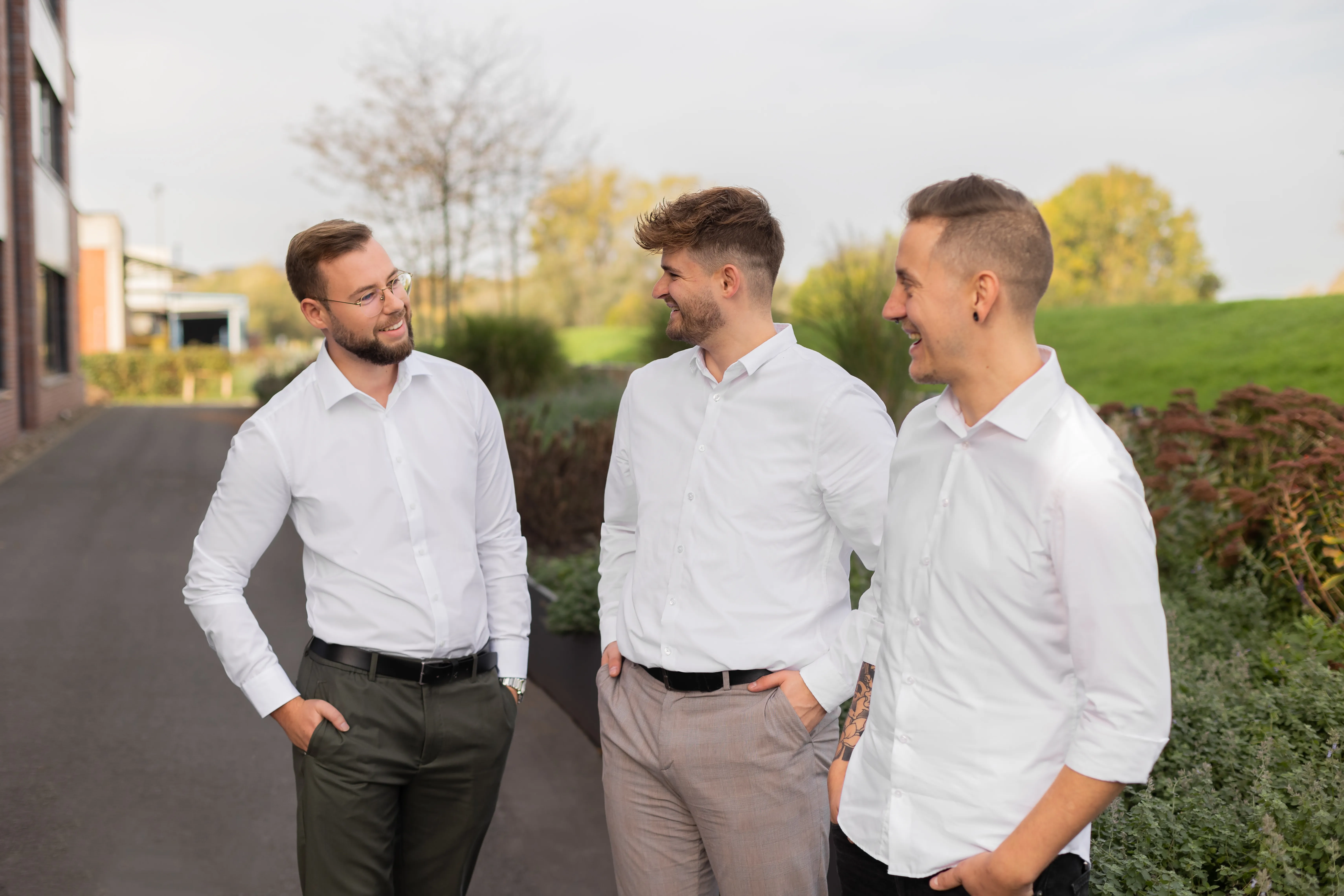 Vier junge Kolleg:innen stehen lächelnd und selbstbewusst vor dem Firmengebäude von REMONDIS Industrie Service.