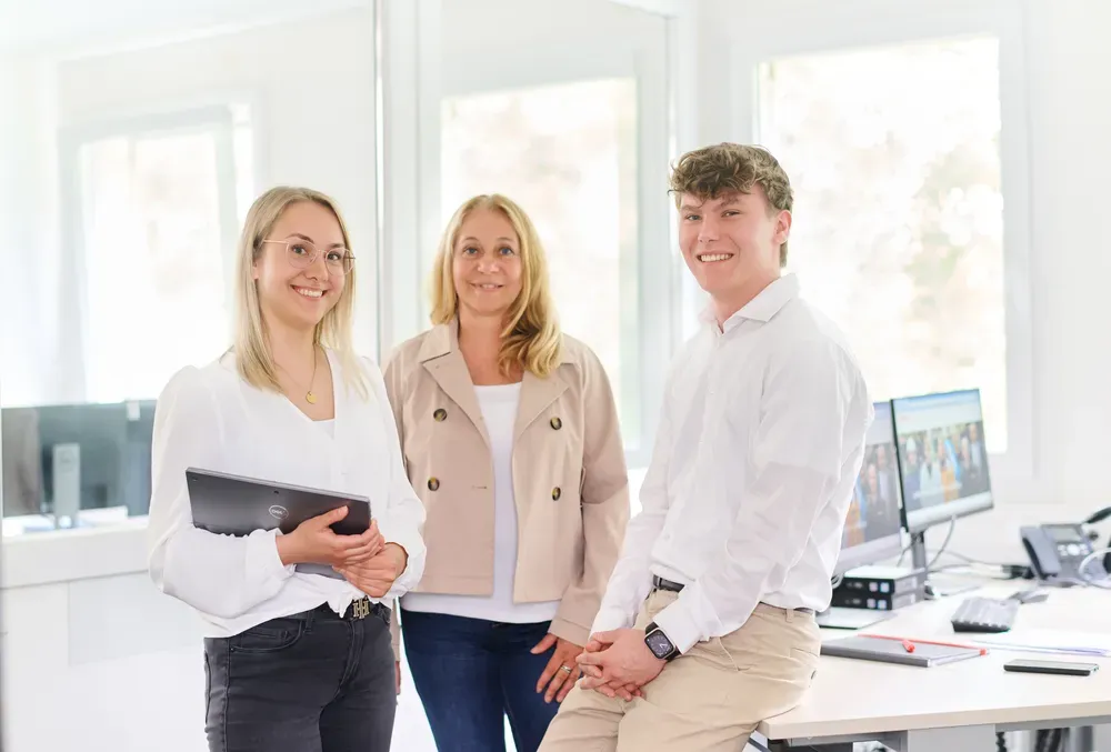 Zwei lächelnde Mitarbeitende von REMONDIS Industrie Service stehen vor einem Firmengebäude und wirken einladend.