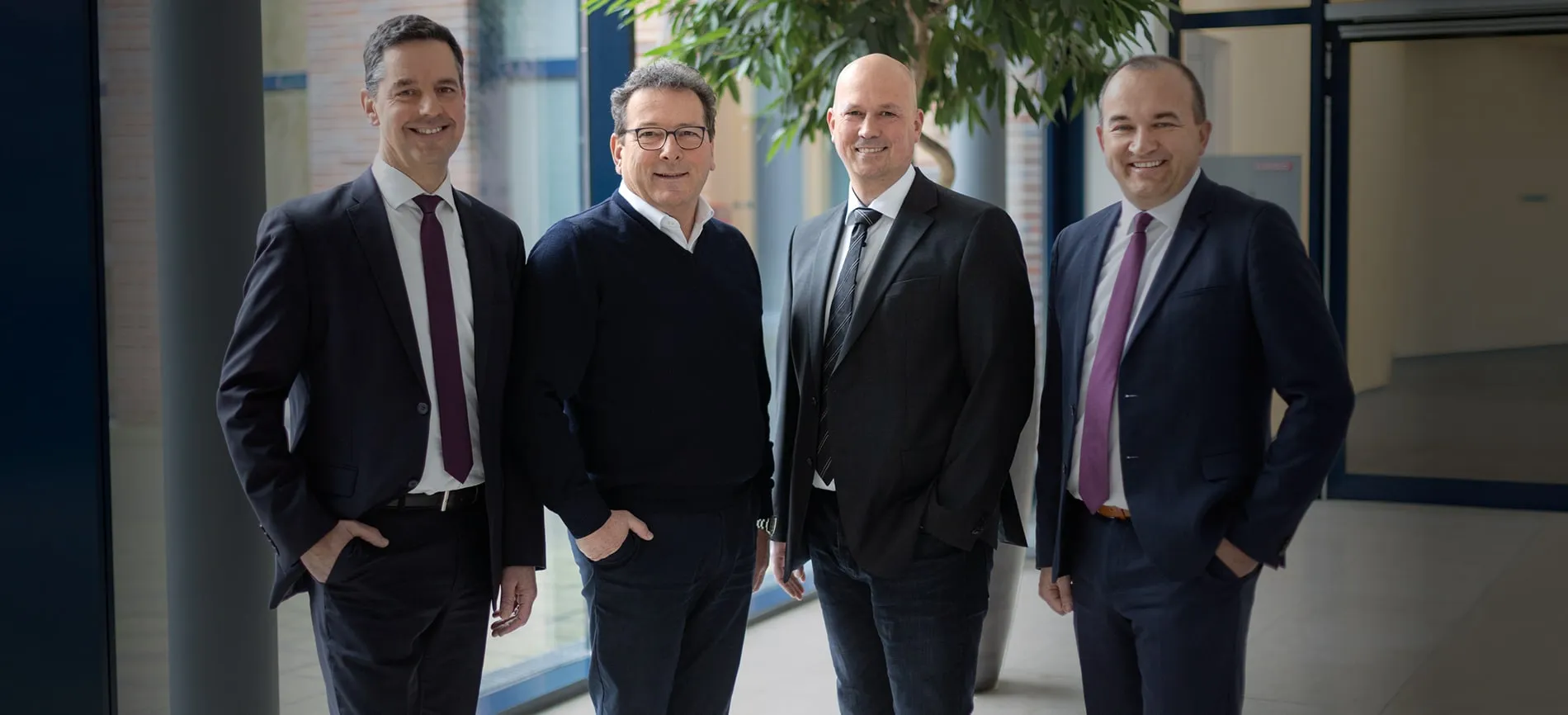 Vier freundlich lächelnde Führungskräfte von REMONDIS Industrie Service stehen gemeinsam im modernen Bürogebäude.