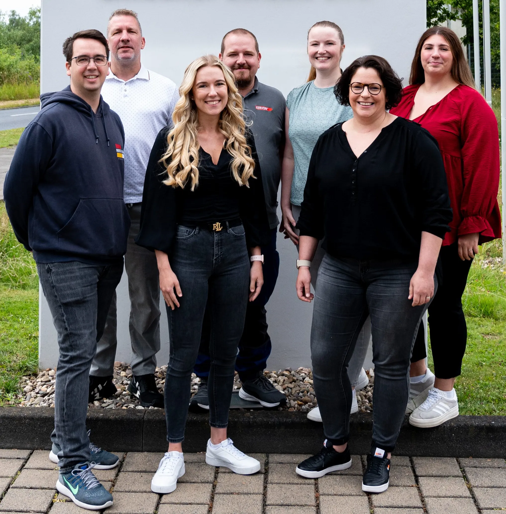 Eine Gruppe von sieben lächelnden Menschen steht vor einem Gebäude von REMONDIS Maintenance & Services GmbH & Co. KG.