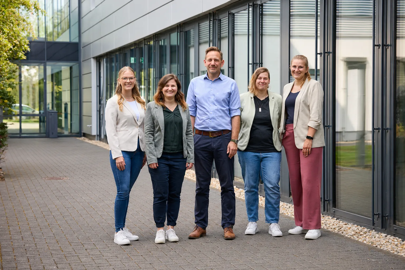 Fünf freundliche Kollegen von REMONDIS stehen vor dem Firmengebäude und freuen sich auf Dich im Team.