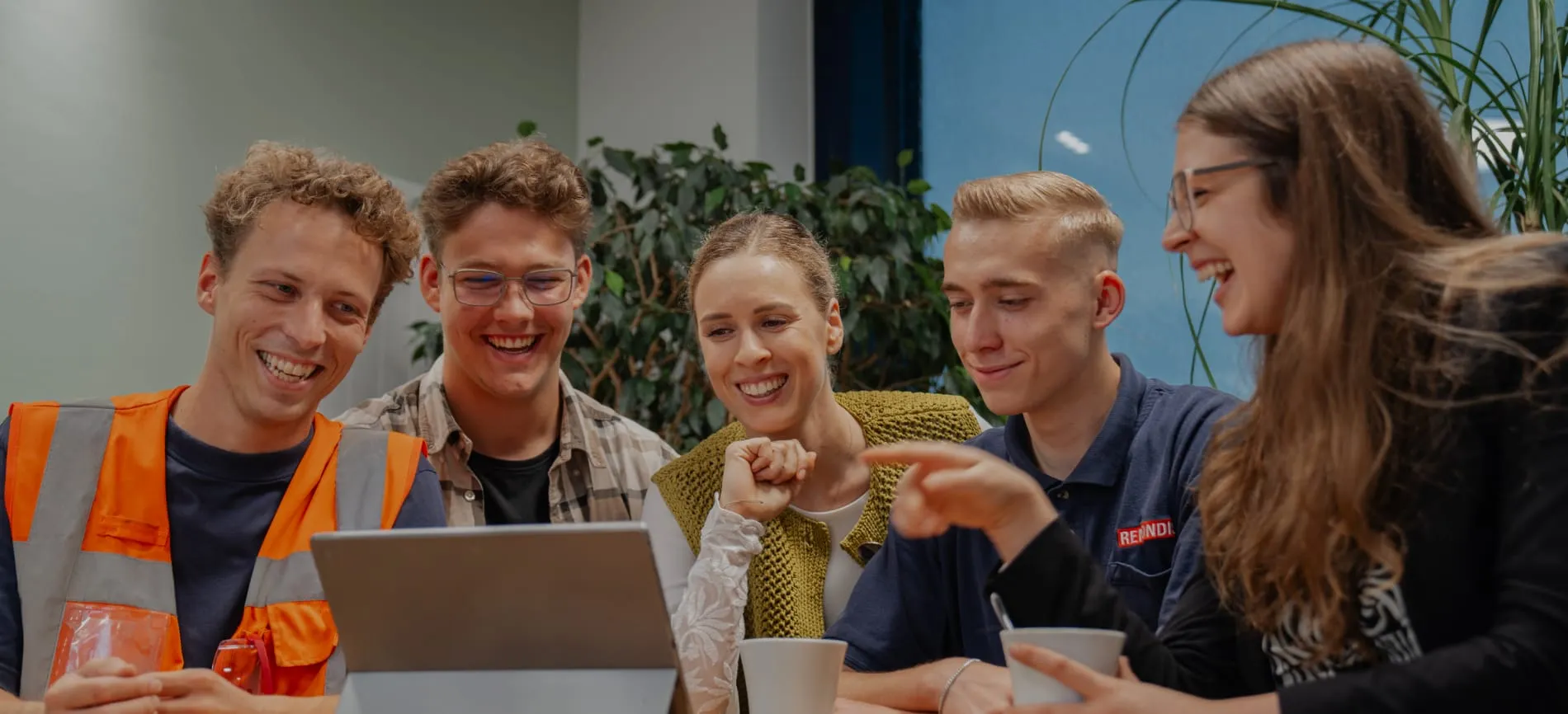 Fünf junge Kollegen lachen gemeinsam bei einer Besprechung am Laptop im Team bei REMONDIS Production GmbH.