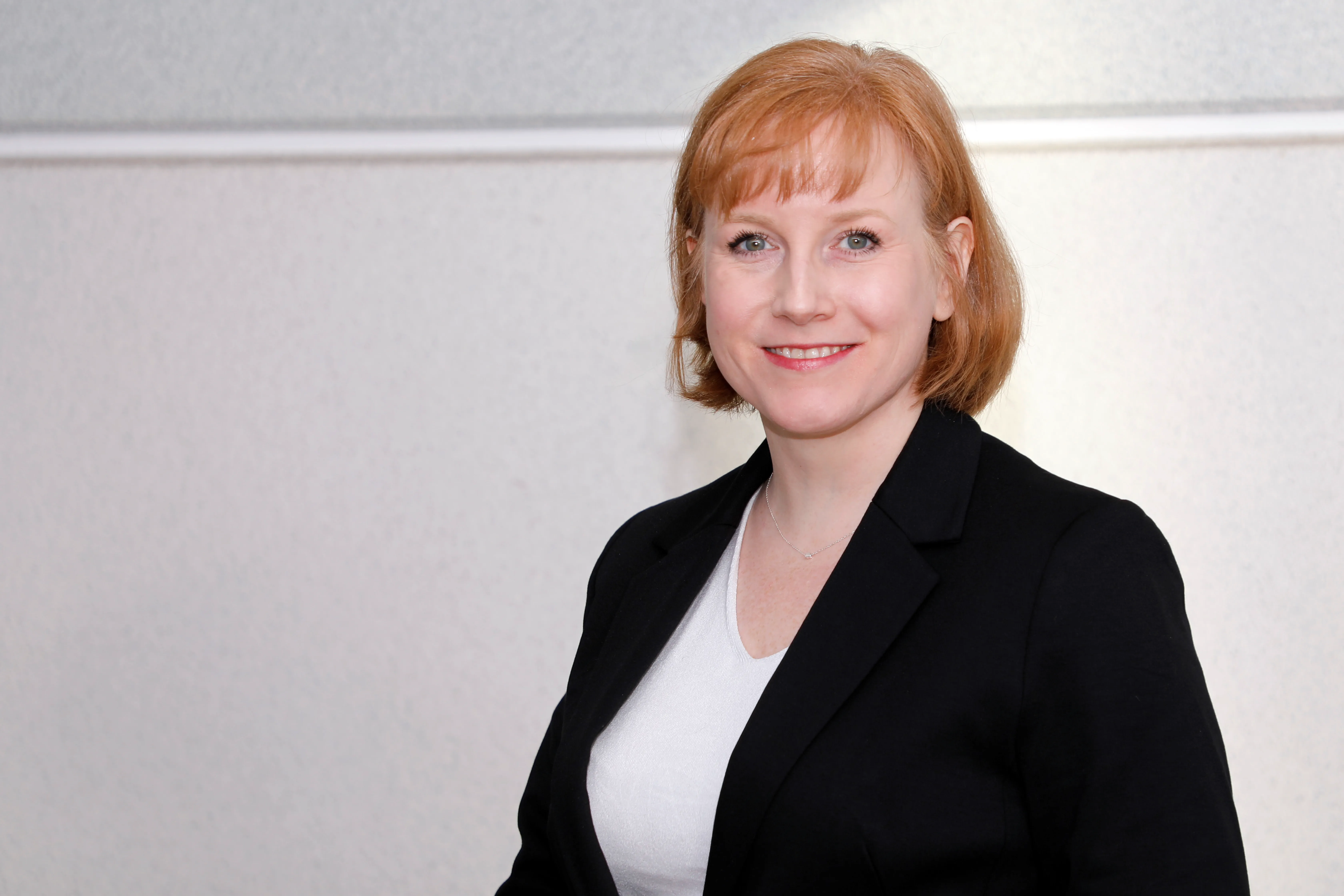 A friendly professional woman in a blazer, smiling confidently, perfect for showcasing Rittal's welcoming IT team.