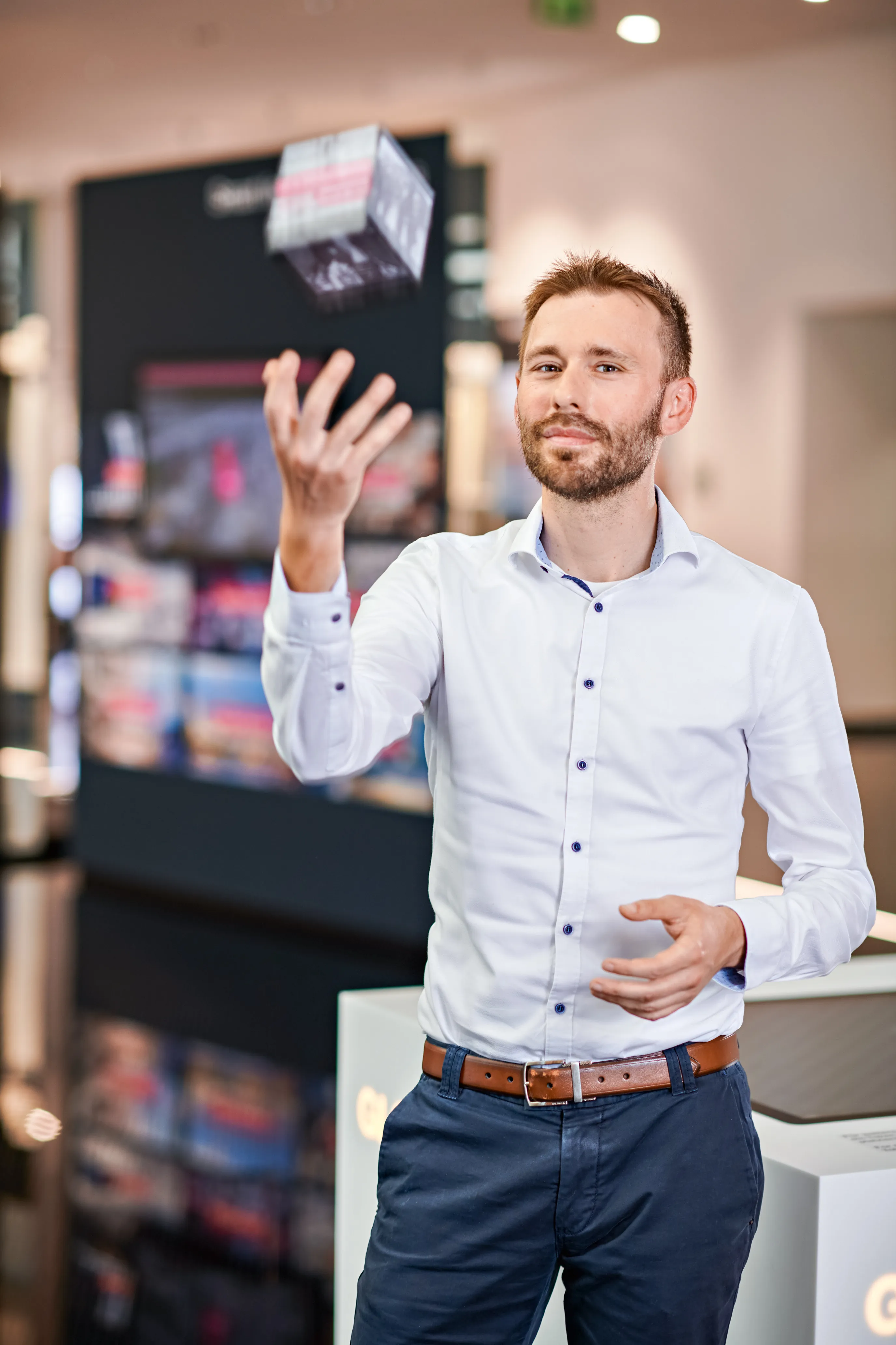 Ein Mann in einem weißen Hemd jongliert mit einem Würfel in einem modernen Büro von Rittal GmbH & Co. KG.