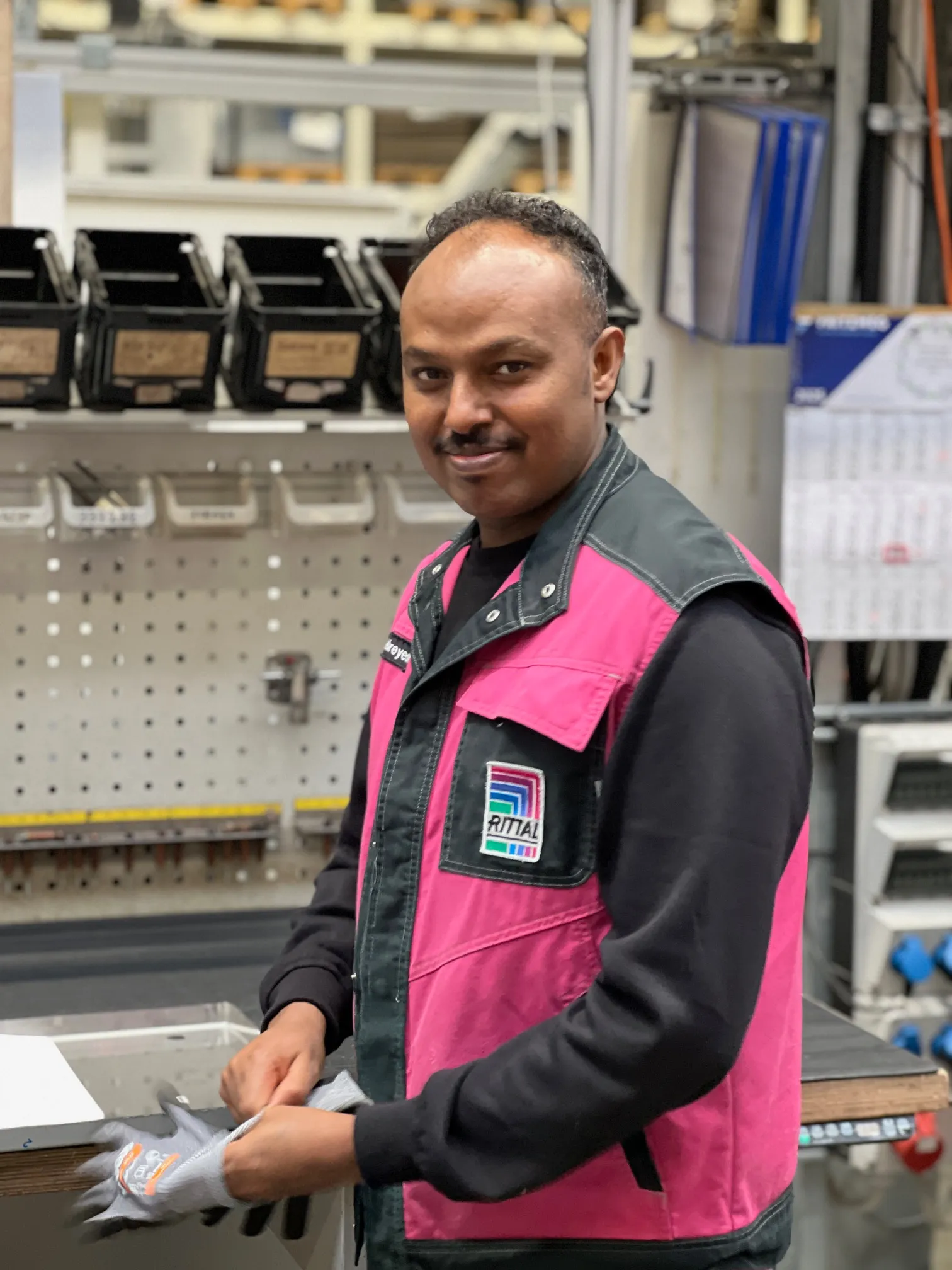 A friendly Rittal employee in a casual office setting, smiling and ready to help you dive into the tech world.