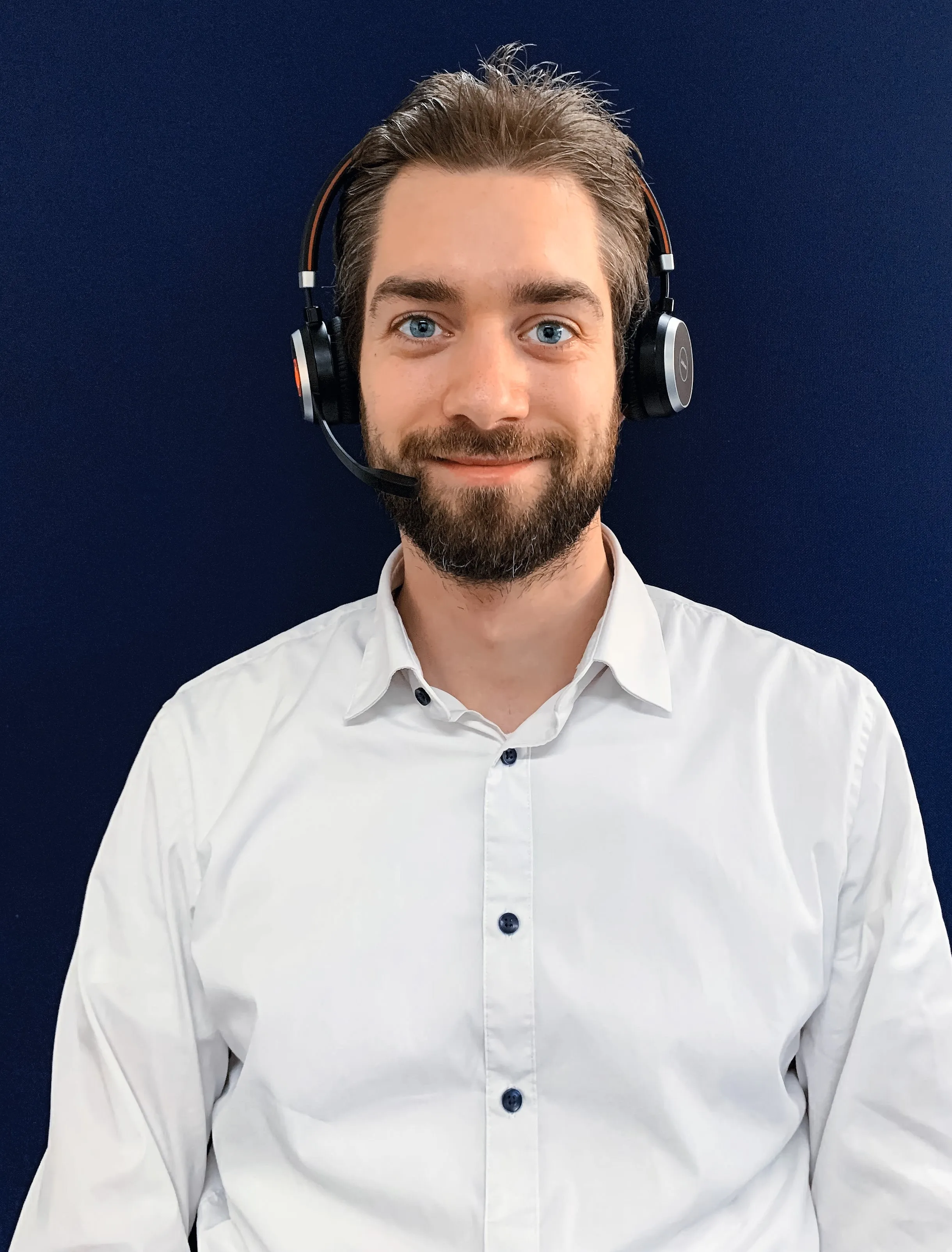Ein lächelnder Mann mit Headset und weißem Hemd, bereit für ein virtuelles Meeting bei Rittal GmbH & Co. KG.