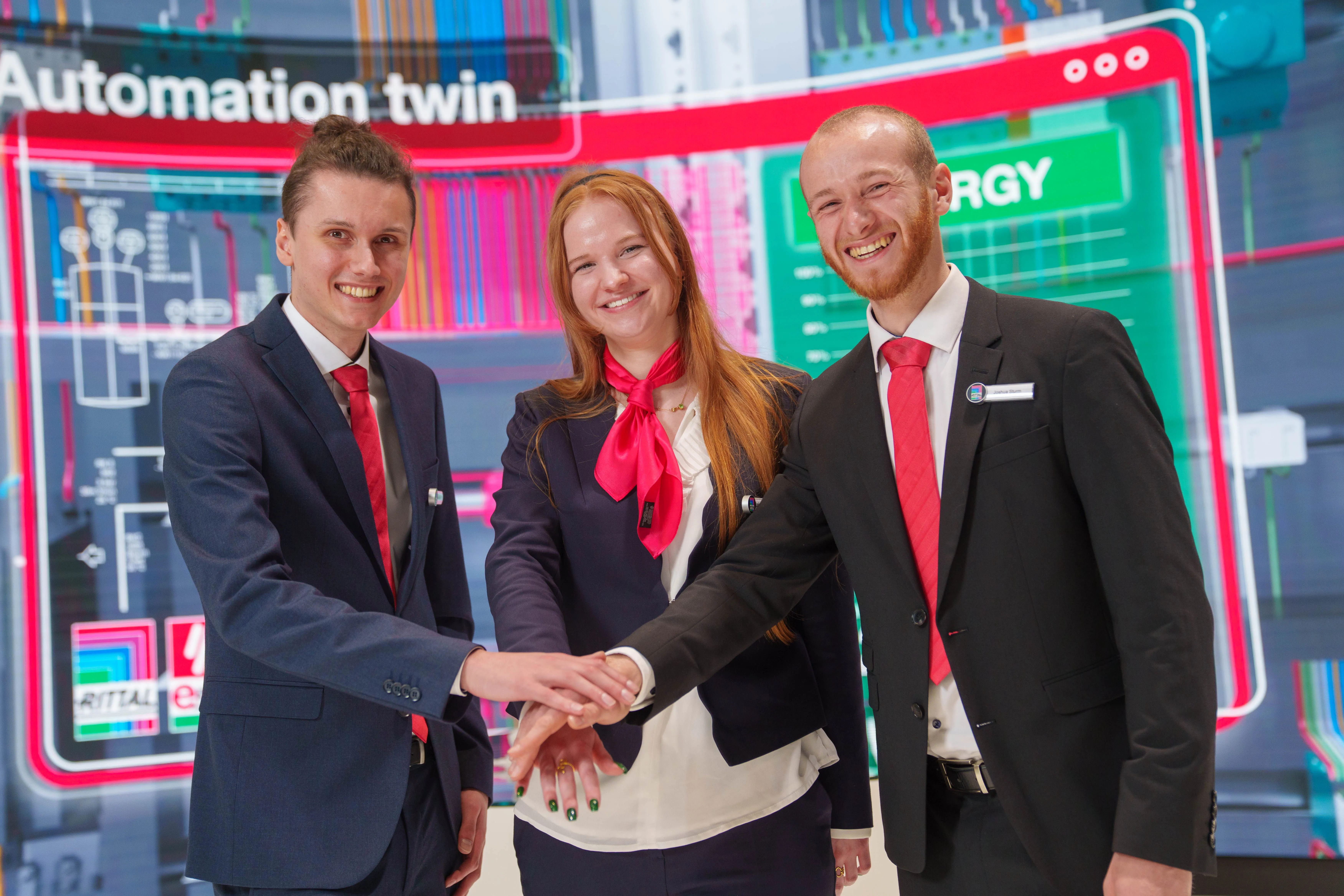 Three smiling colleagues in suits with red ties at Rittal GmbH & Co. KG stand, showcasing teamwork in IT industry.