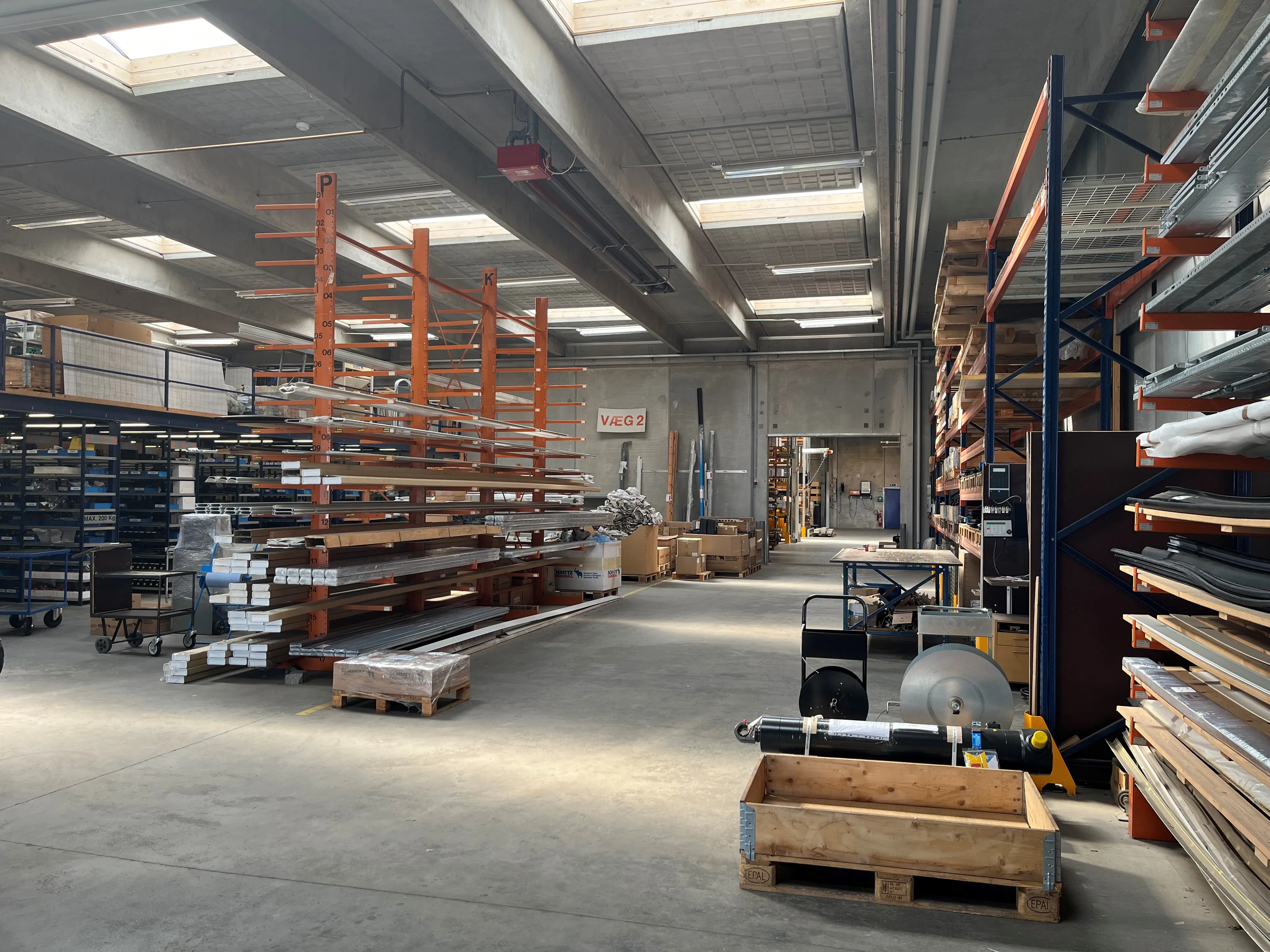 A spacious warehouse at Schmitz Cargobull AG with organized shelves, packed with automotive materials.