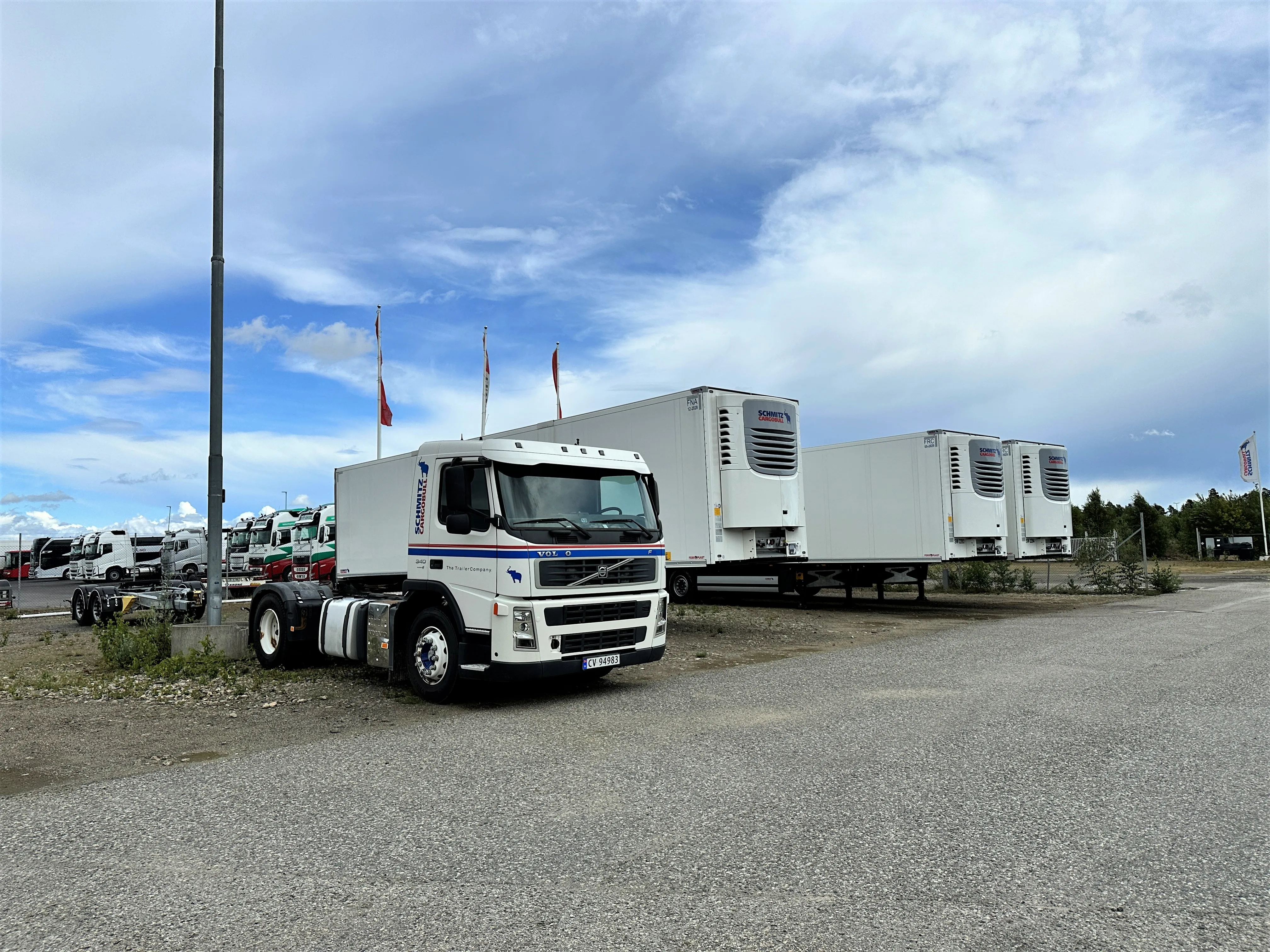 A Schmitz Cargobull truck parked outdoors, with trailers and a clear blue sky in the background.
