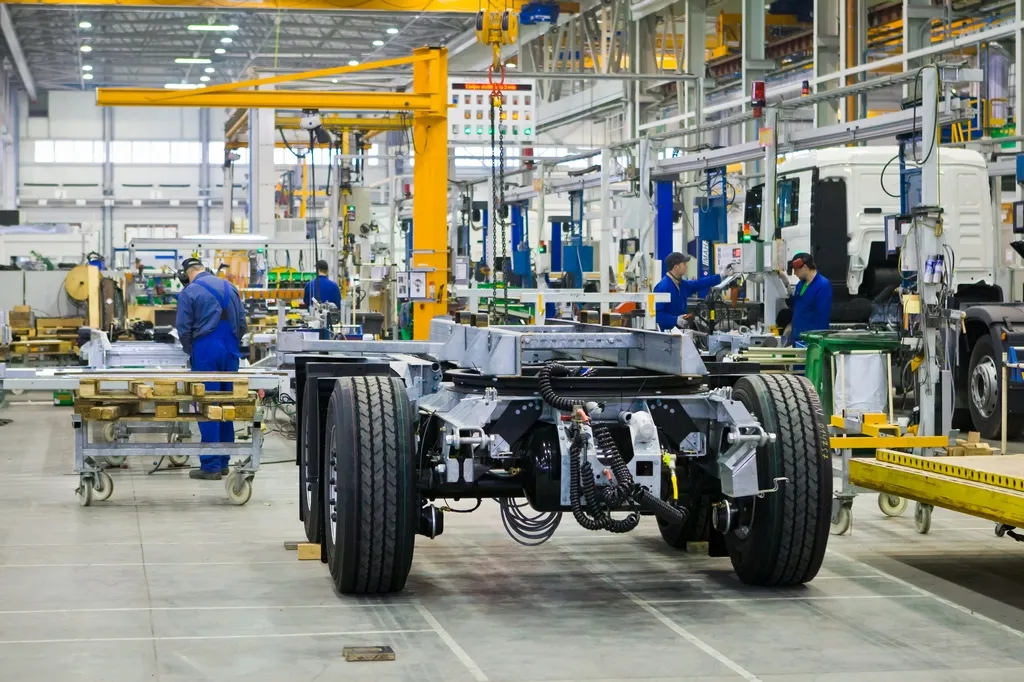 Workers in blue uniforms assembling truck chassis at Schmitz Cargobull AG’s automotive factory.