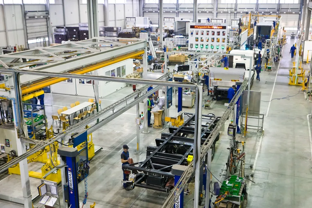 A bustling Schmitz Cargobull factory floor with workers assembling truck trailers.