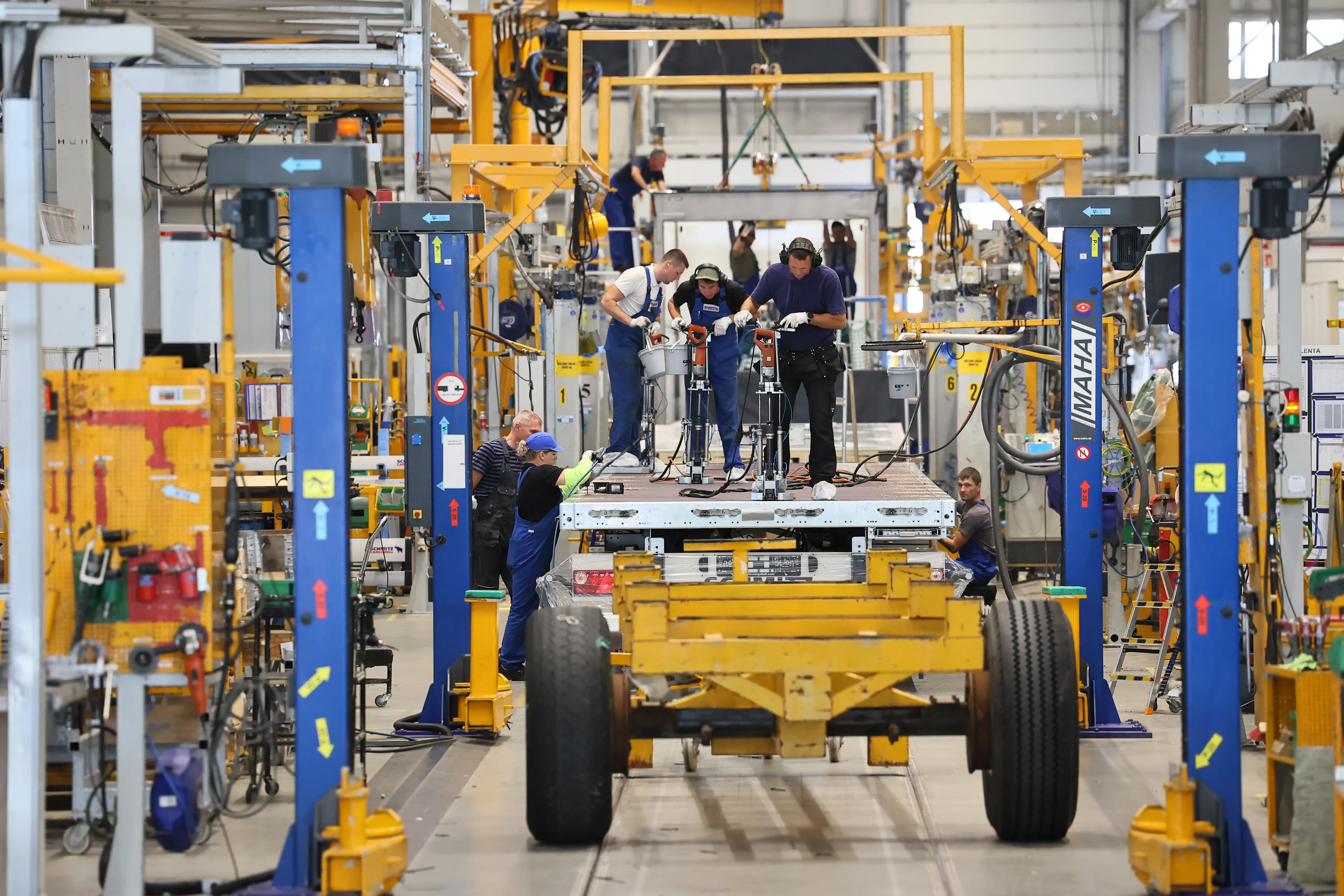 Assembly line at Schmitz Cargobull AG with team members building vehicle components in a bustling automotive factory.