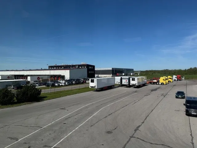 A sunny day at Schmitz Cargobull AG's lot, showcasing parked trailers and trucks ready for action.