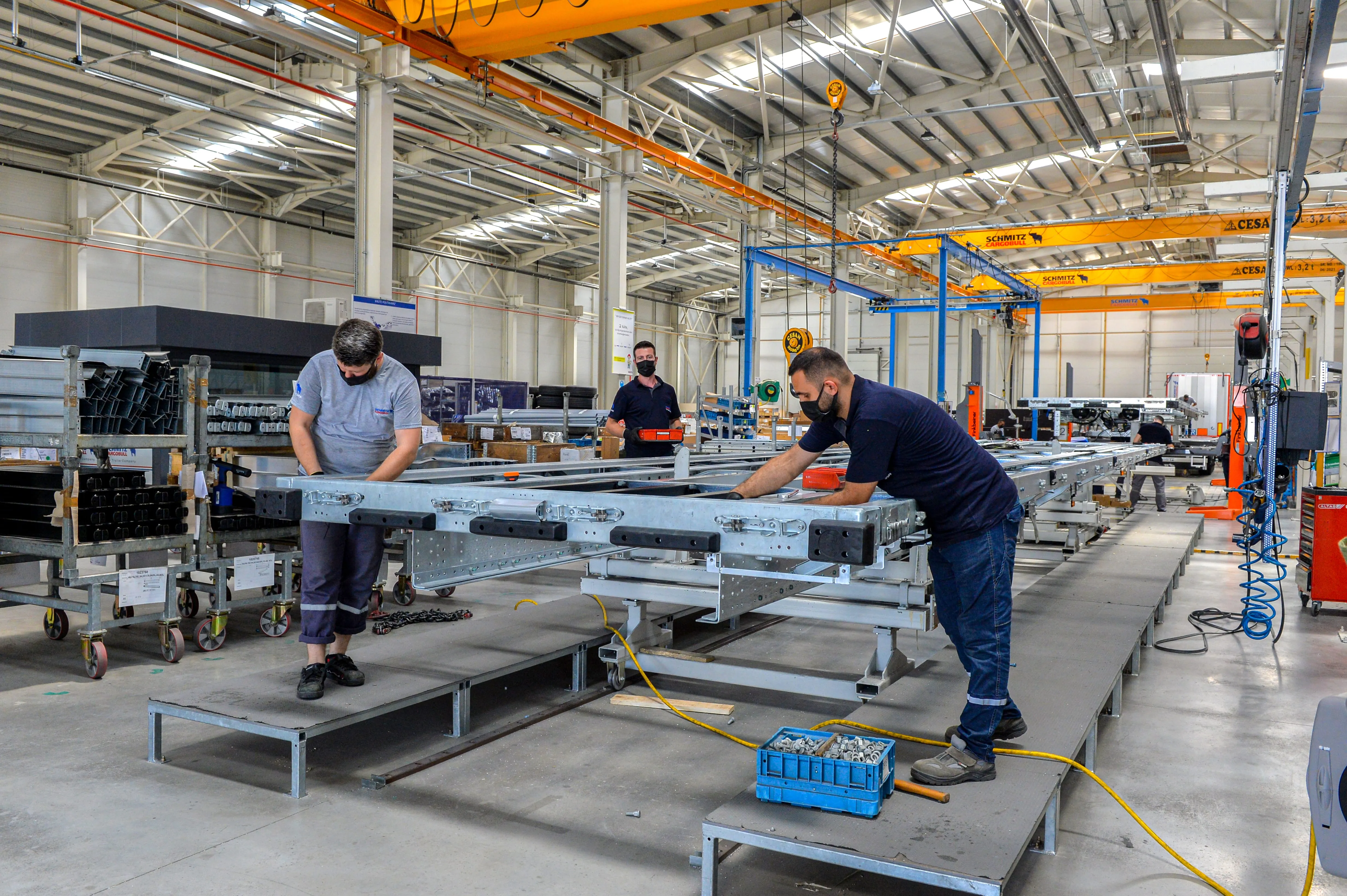 Workers assembling trailer components in a spacious Schmitz Cargobull AG factory.