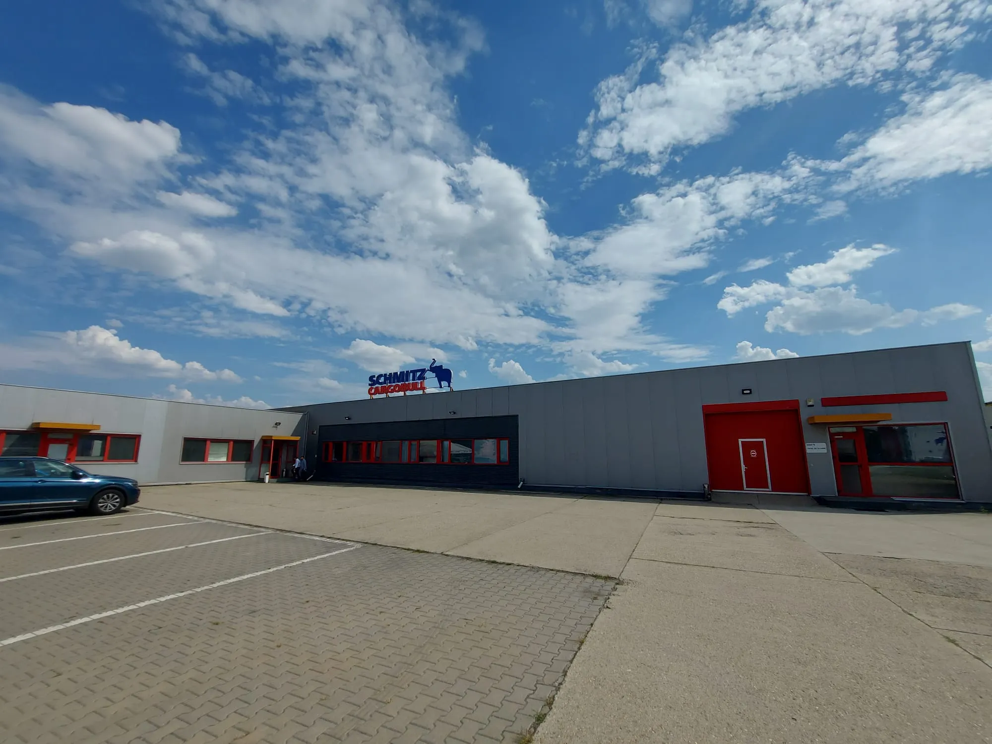 Modern Schmitz Cargobull AG building under a bright blue sky, showcasing their automotive industry presence.