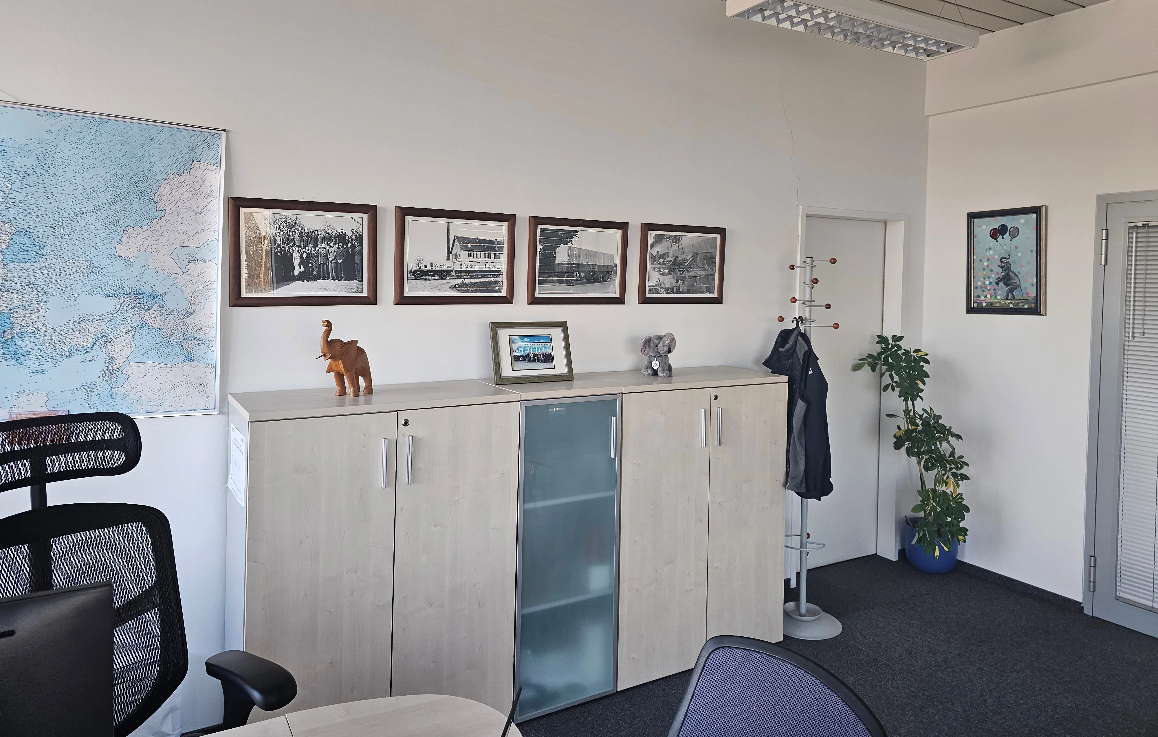 A cozy office corner at Schmitz Cargobull AG, featuring vintage truck photos, a world map, and charming decor.
