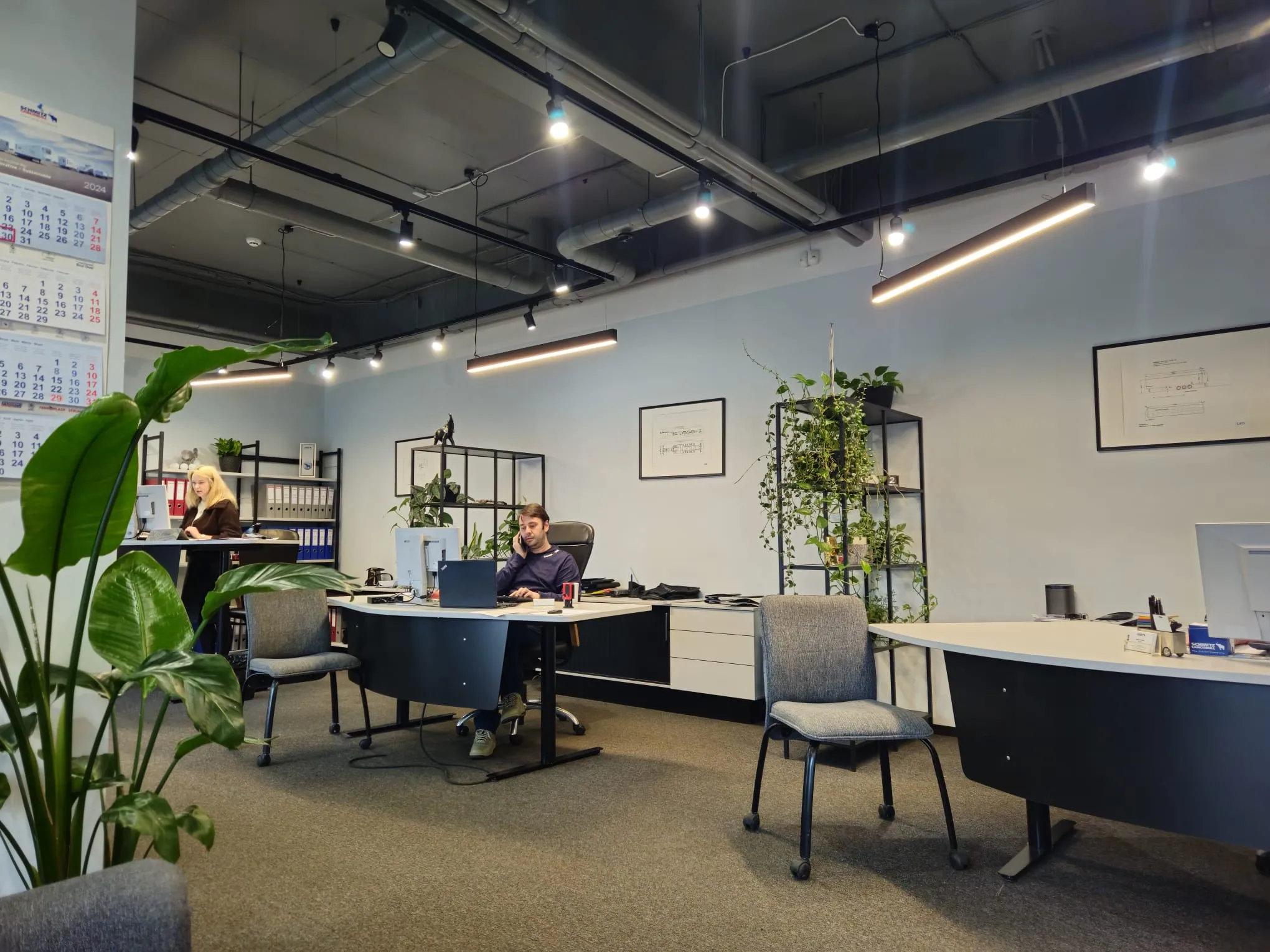 Modern office space at Schmitz Cargobull AG, featuring employees working at desks surrounded by plants and industrial decor.