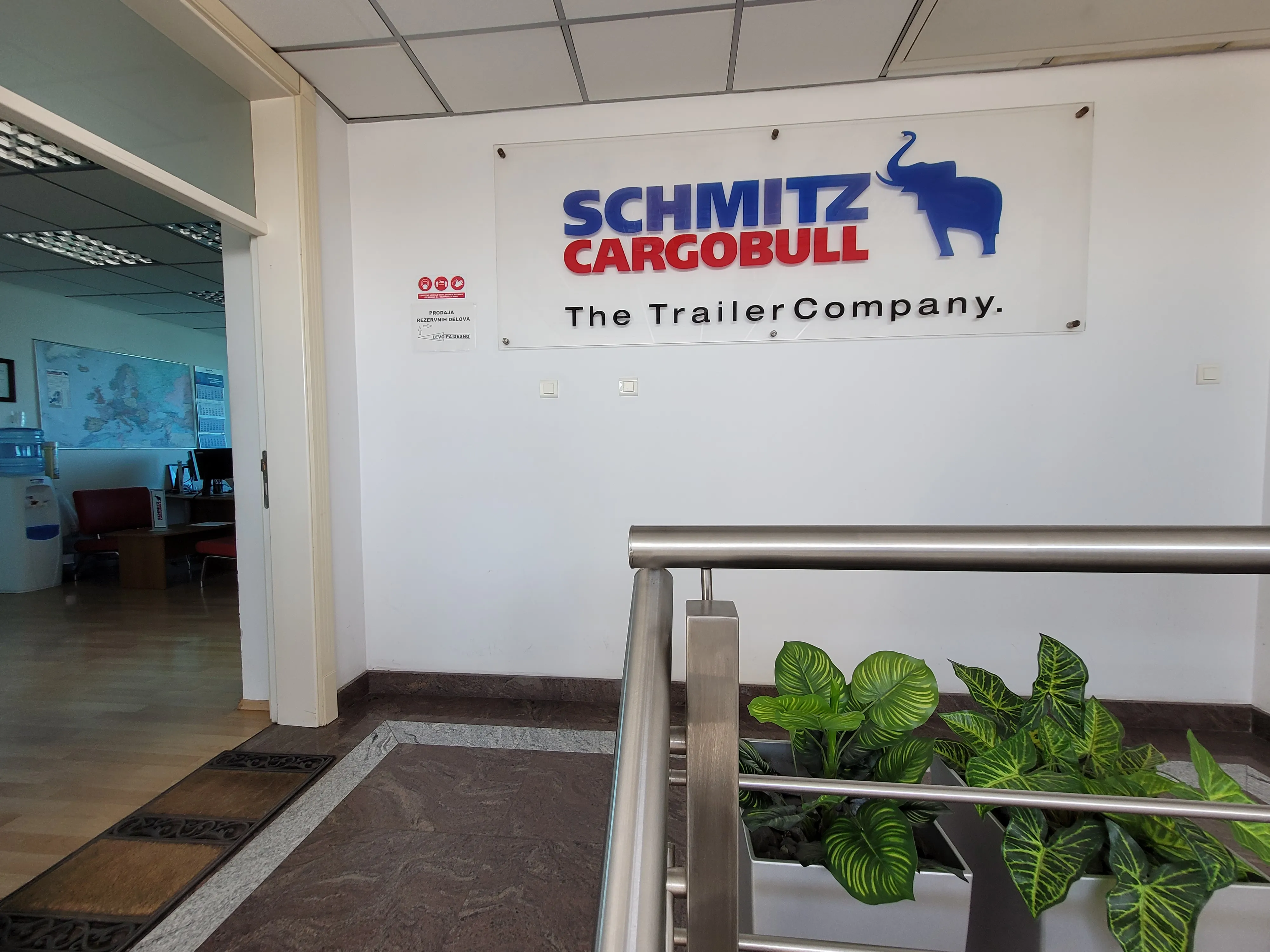 Welcome to Schmitz Cargobull AG! Check out our office vibes with a cool sign, leafy plants, and a peek inside a workspace.