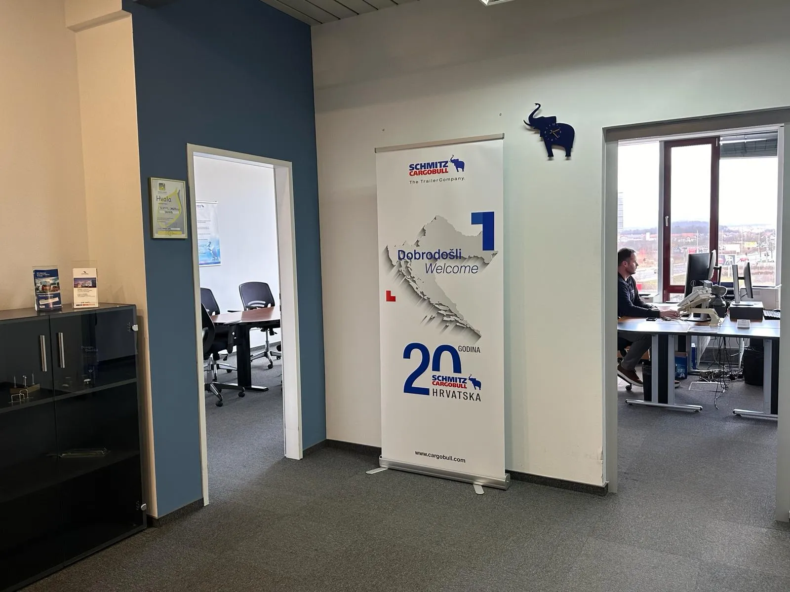 Cozy office space at Schmitz Cargobull AG, featuring a welcome banner and a glimpse into a meeting room and workspace.