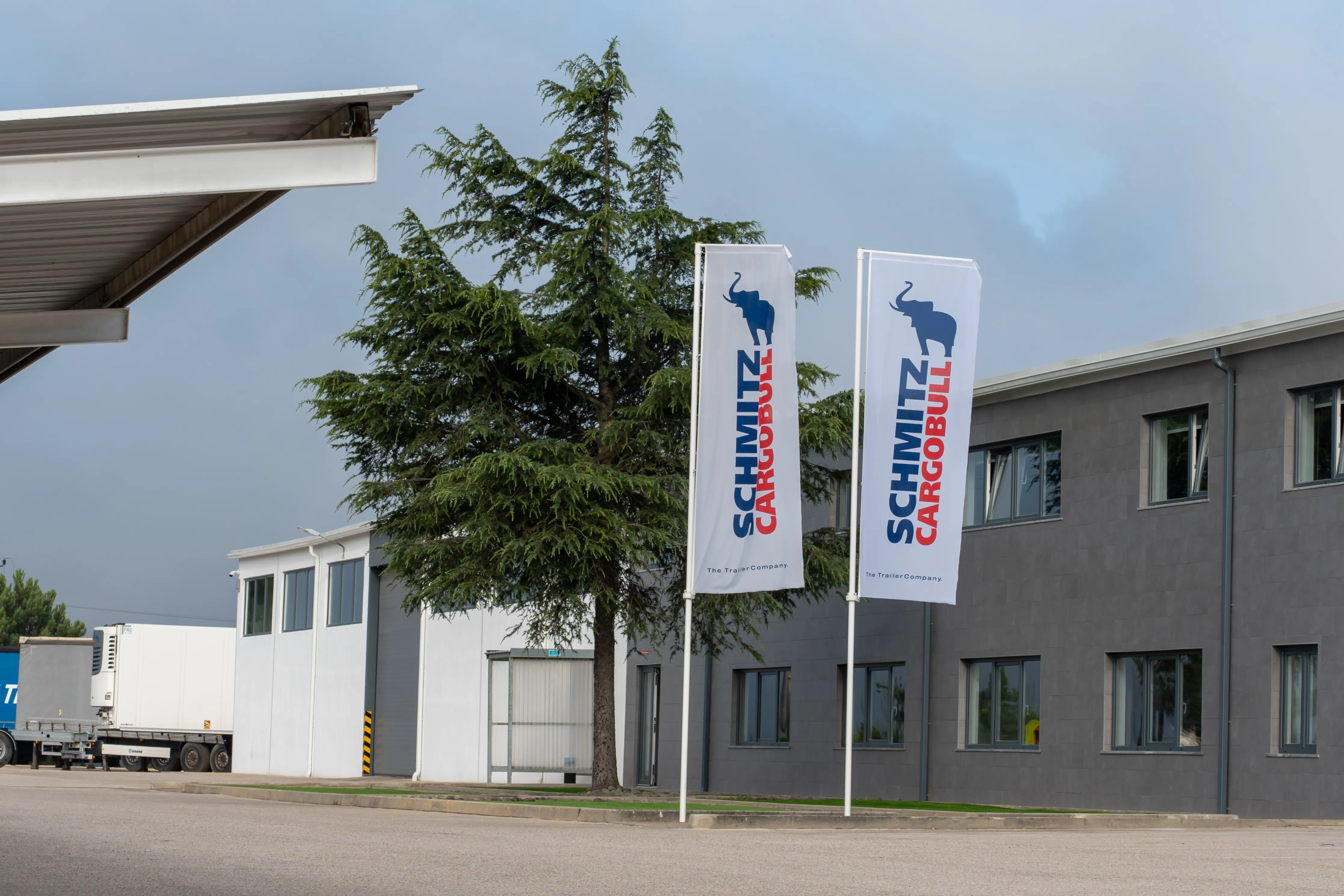 Schmitz Cargobull AG office with company flags and parked trailer truck, showcasing the automotive industry vibe.
