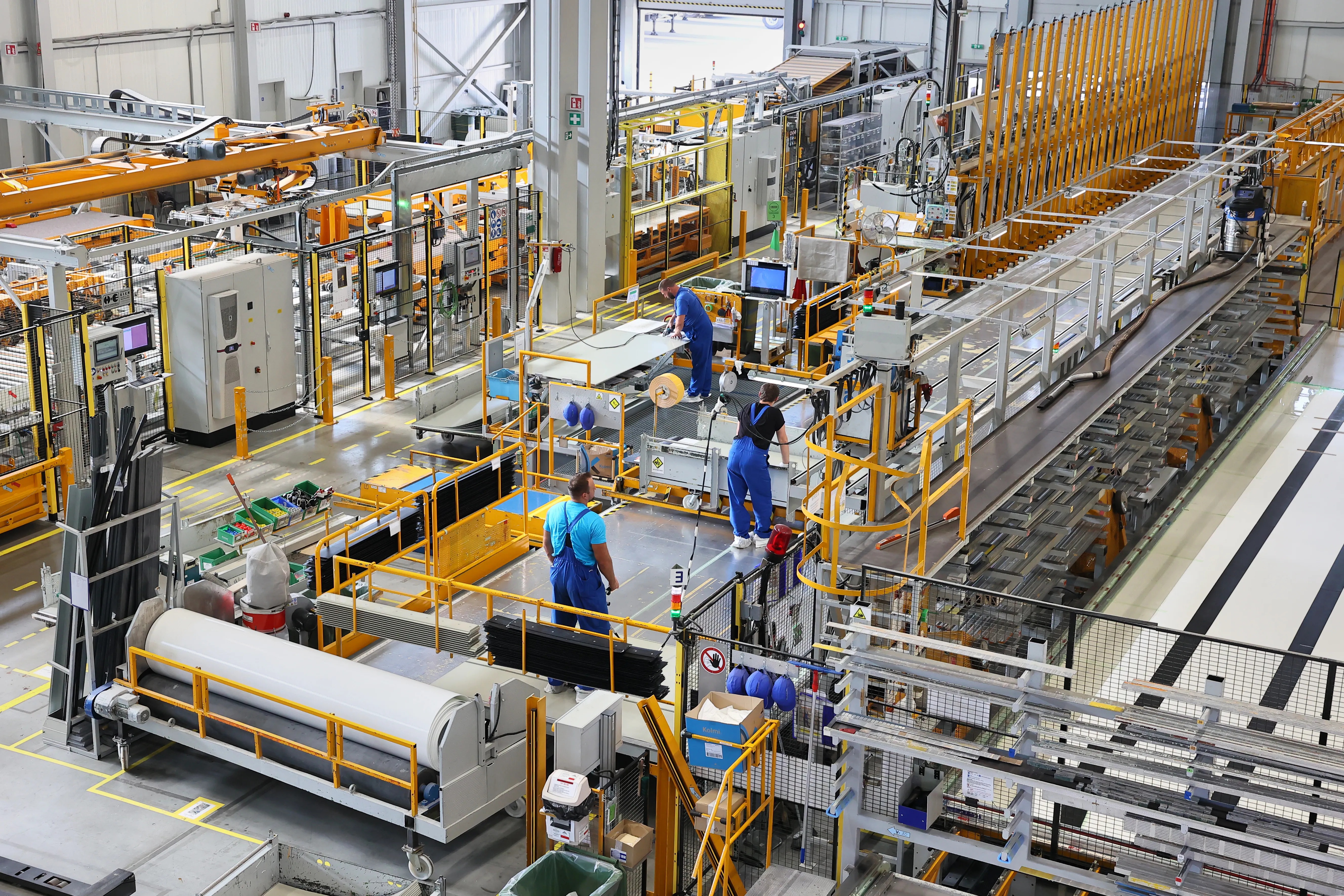 A bustling Schmitz Cargobull AG factory floor with workers assembling automotive parts.